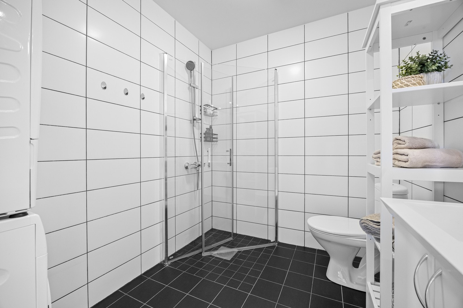 Pent, flislagt bad med varmekabler. Badet er innredet med dusjnisje med innfellbare dusjdører, wc, hvit baderomsinnredning med speil. Praktisk nisje til vaskemaskin og tørketrommel. Galleribilde