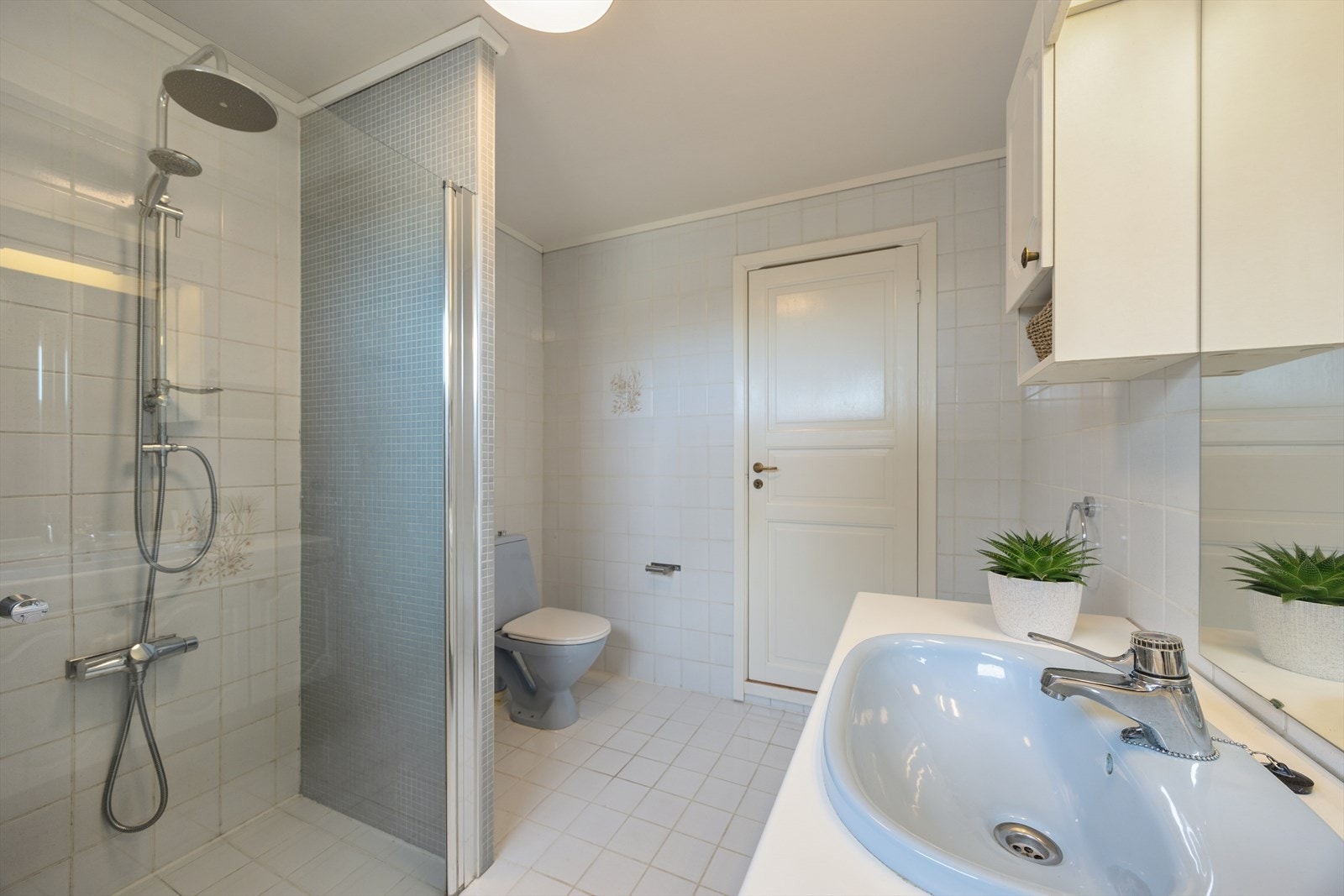 Flislagt bad i underetasje innredet med servant, toalett og dusjløsning. Galleribilde