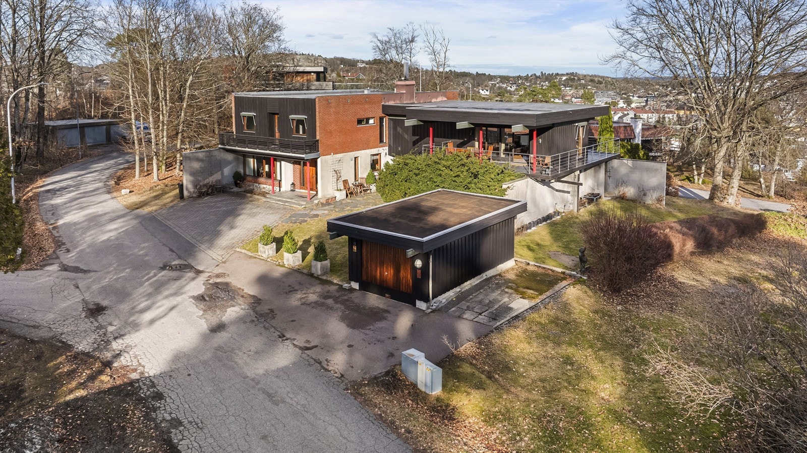 Flyfoto som viser eiendommen med garasje og gårdsplass. Galleribilde