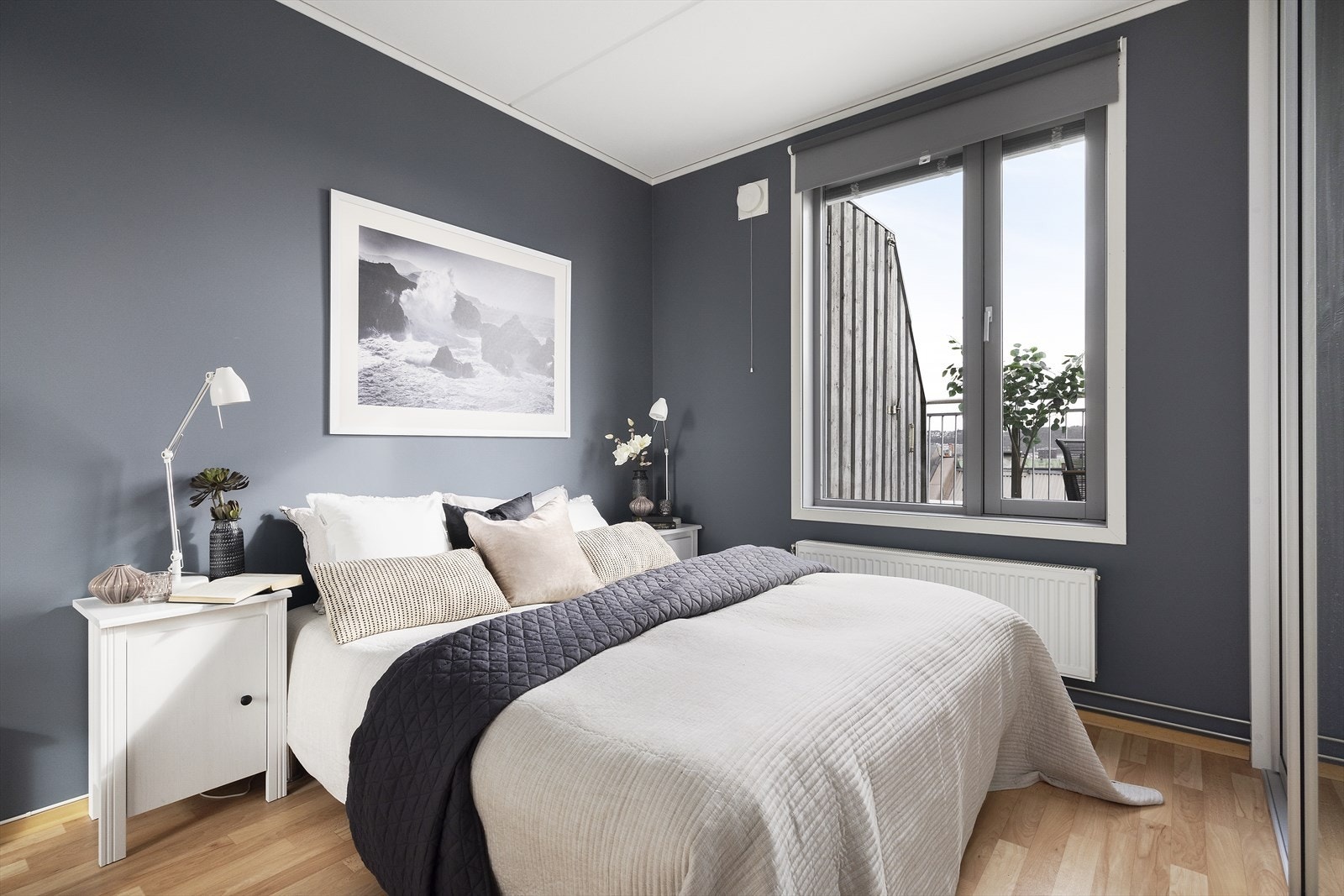 Lyst soverom med vindu mot det fri og god plass til seng og tilhørende møblering Galleribilde