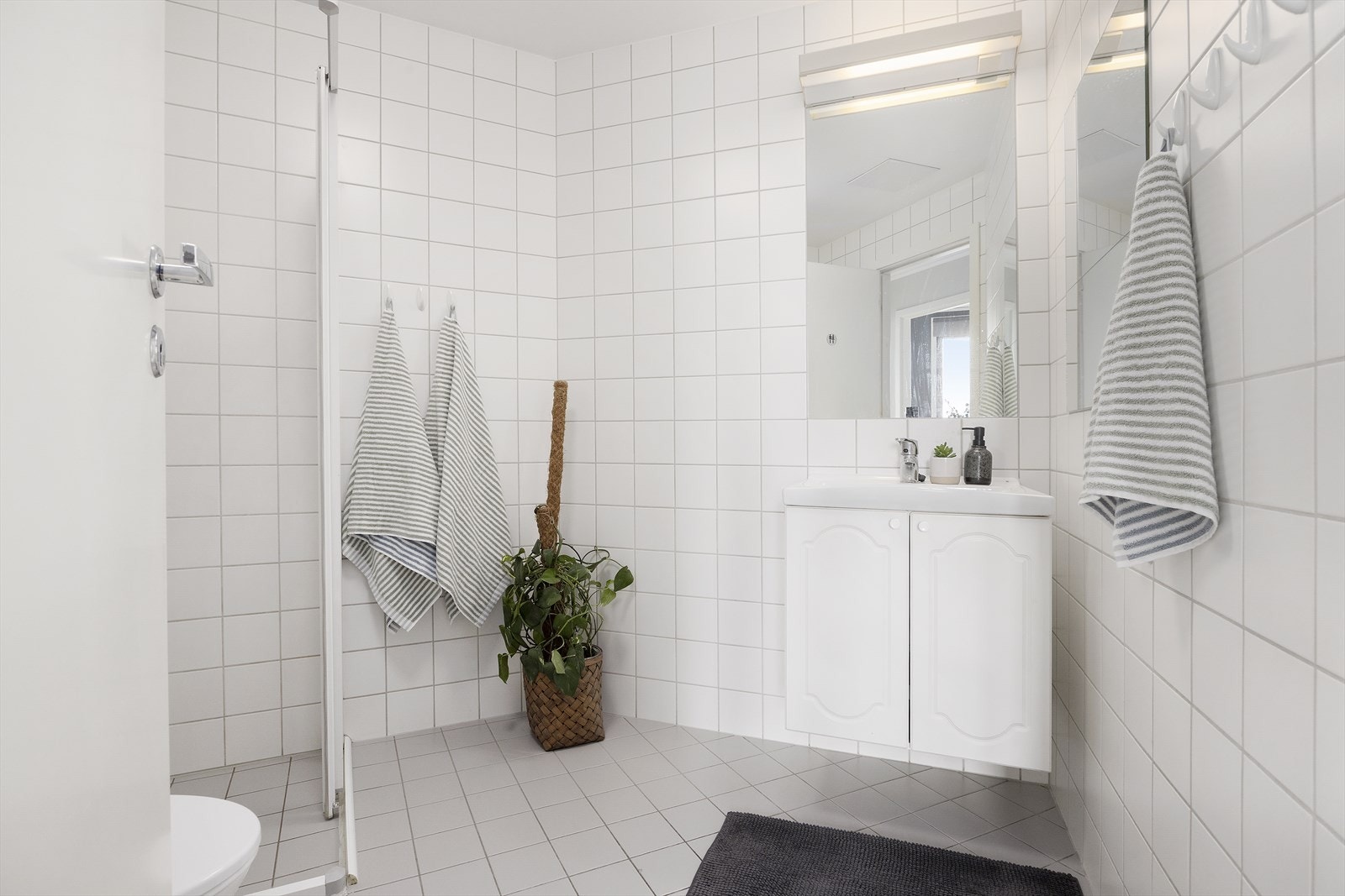 Flislagt bad med servant, toalett, dusjhjørne, mekanisk avtrekk og elektriske varmekabler i gulvet Galleribilde