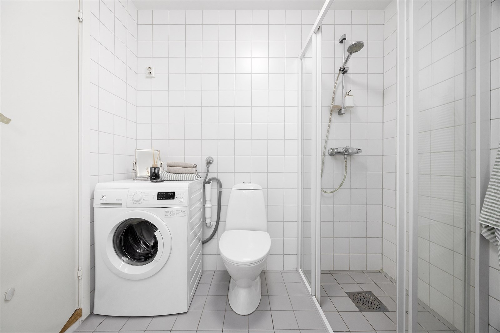 Badet har eget opplegg for vaskemaskin, dusjhjørne, toalett og flislagte overflater Galleribilde