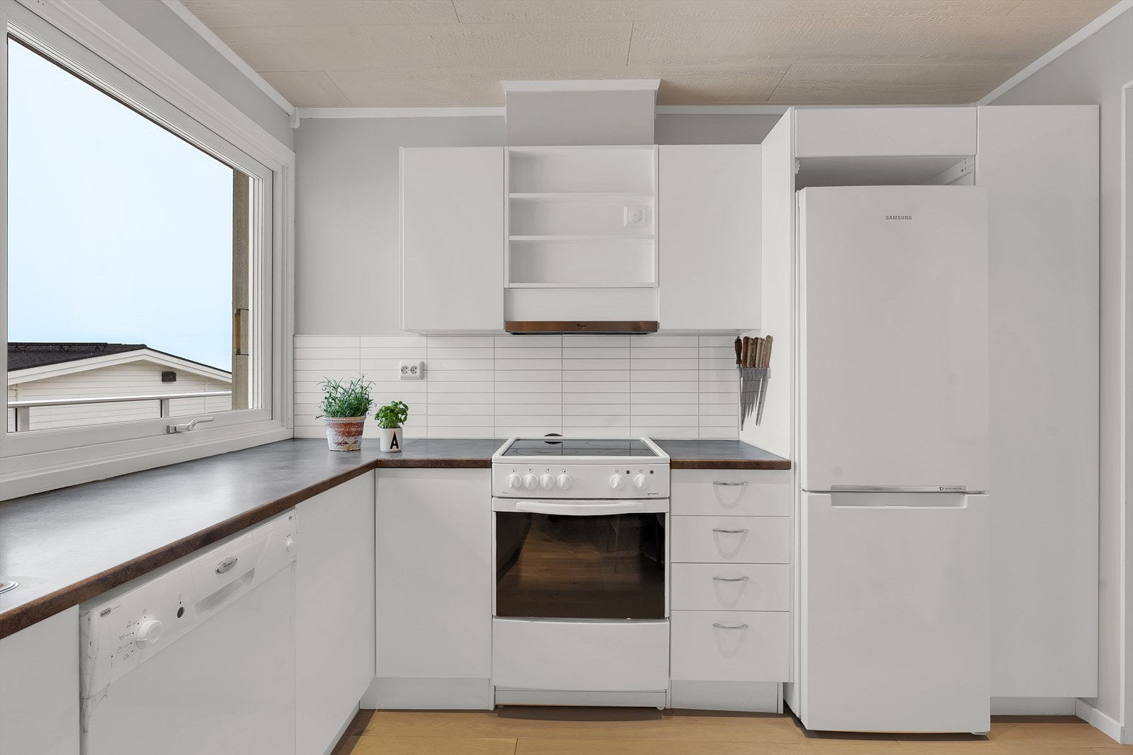 Lyst kjøkken med slette fronter og god oppbevaringsplass i hyller og skuffer. Galleribilde