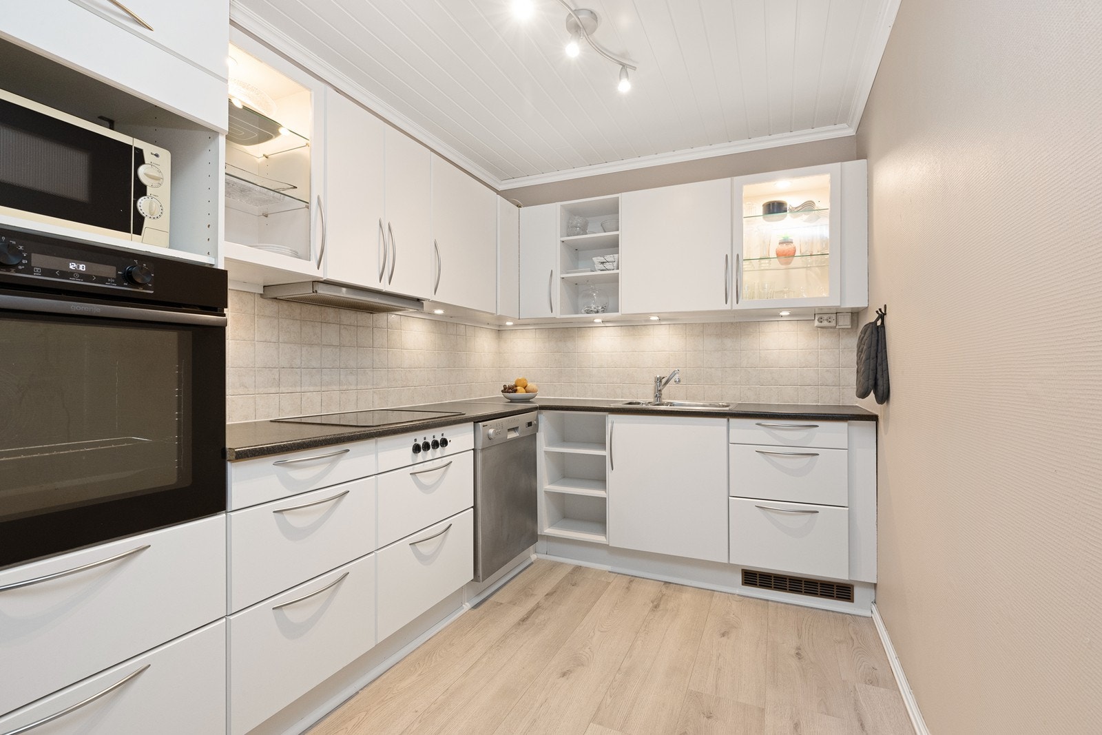 Det er montert kjøkkenventilator med avtrekk ut, og fliser på veggen mellom skapene. Galleribilde