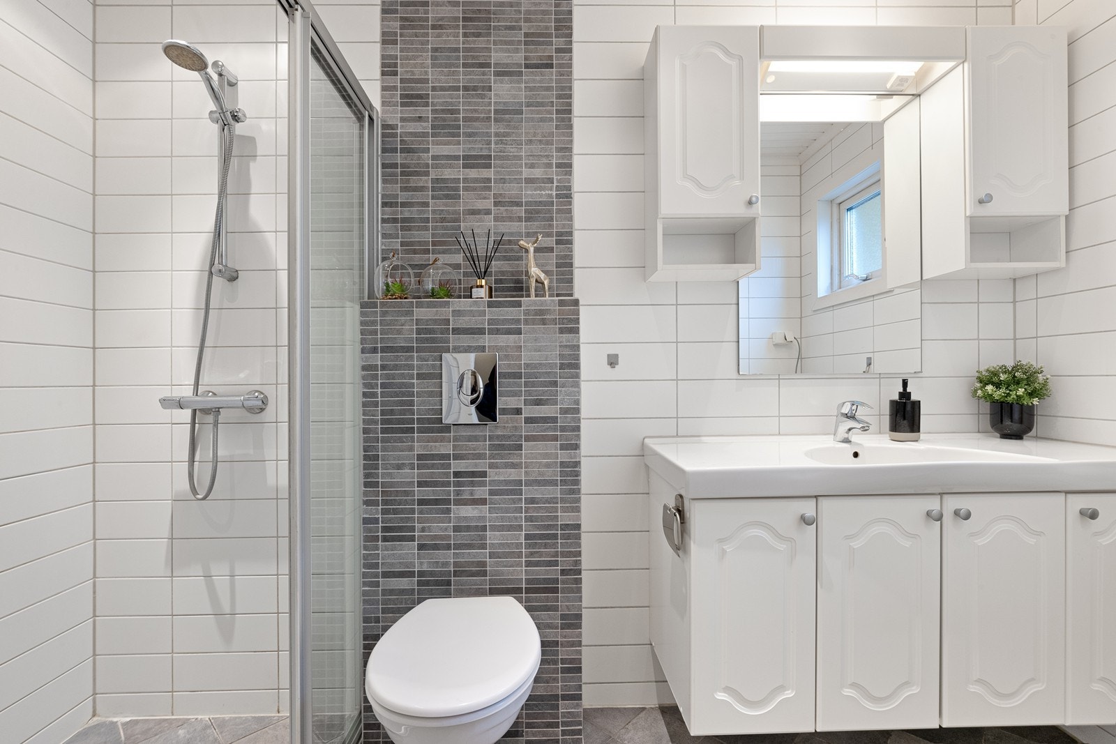 Badet har servantinnredning med lyse fronter og speilskap som gir god oppbevaringsplass. Galleribilde