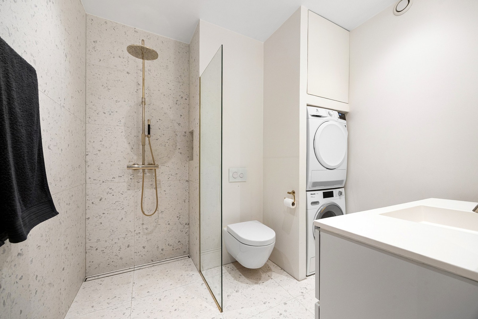 Det har et moderne uttrykk med slette, lyse vegger og store fliser på gulv og i dusjsonen. Dusjnisjen er utstyrt med en stilren regnfallsdusj. Galleribilde