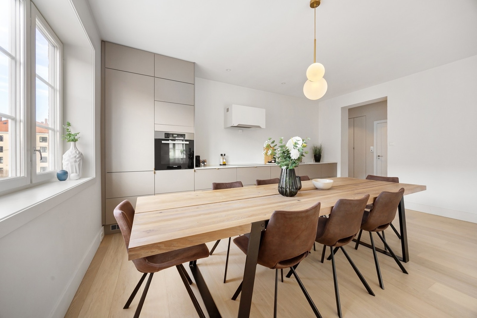 Innredningen fra HTH har et moderne uttrykk med glatte, grå fronter, takhøye høyskap, og en elegant benkeplate i stein. Galleribilde