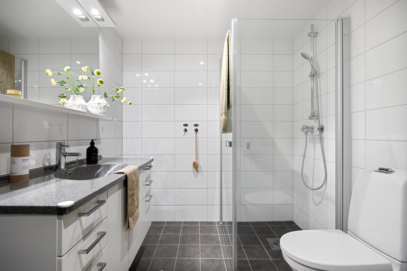 Leilighetens bad er stilrent med keramiske fliser, innfelte spotter og vannbåren gulvvarme som sikrer en lun og behagelig start på dagen. Galleribilde