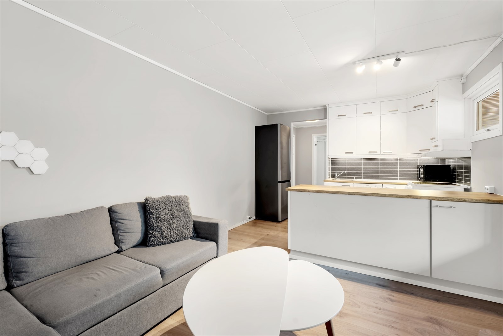 Slette vegger med behagelig fargevalg og åpen samt sosial løsning mellom stue og kjøkken Galleribilde