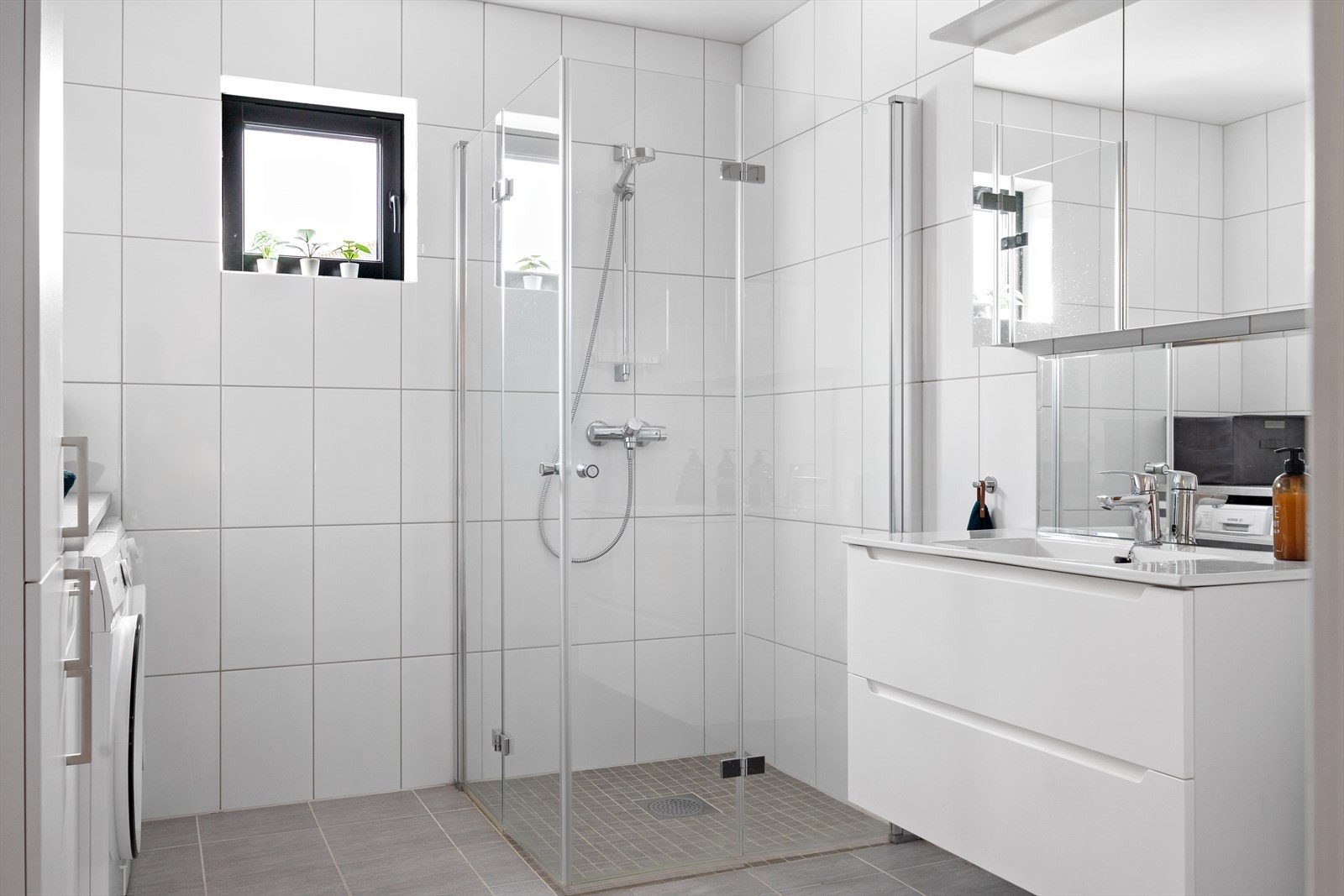 Lyst og helfliset bad som byr på både estetikk og funksjonalitet. Med moderne innredning, vegghengt toalett og dusjhjørne med glassdører, har badet et tidløst preg. Galleribilde