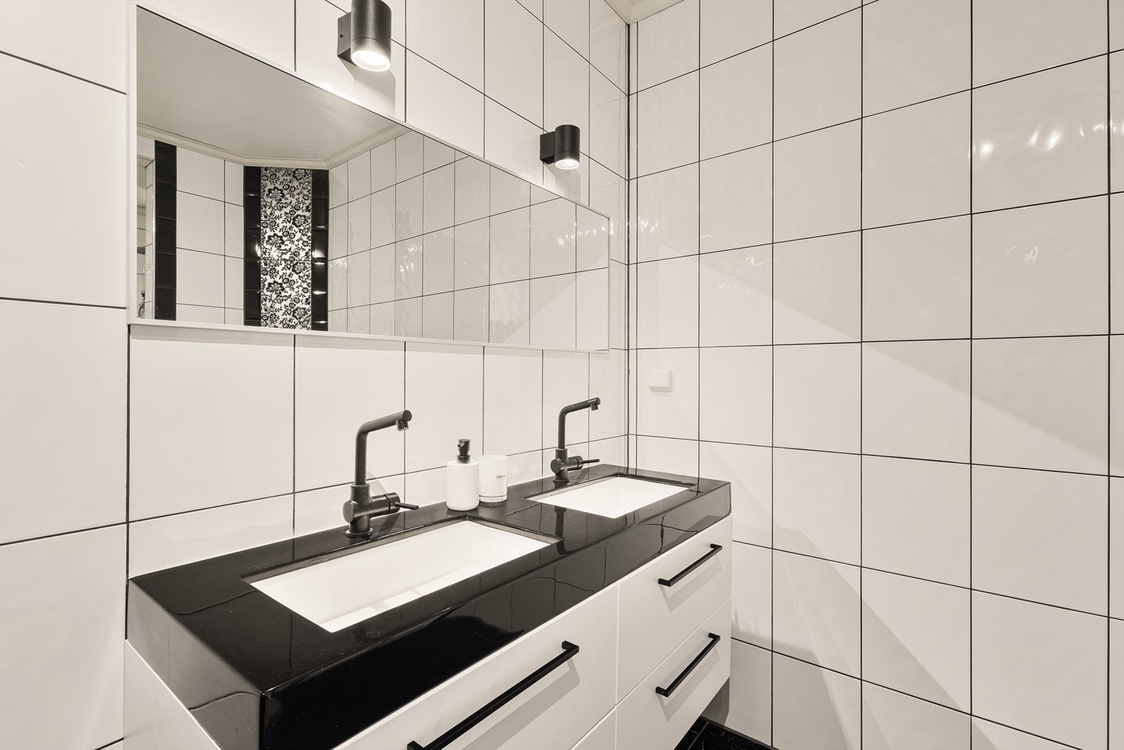 Baderomsinnredningen har hvite fronter og heldekkende sort og hvit servant Galleribilde