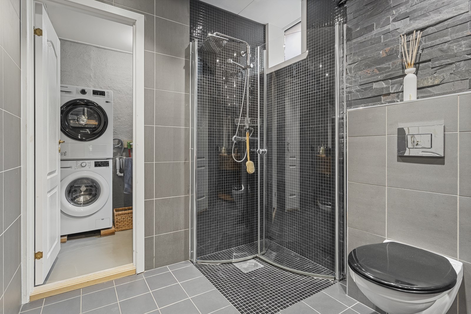 Baderommet er innredet med vegghengt wc, håndvask, underskap, stort speil over vask og vendbare dusjdører i glass. Galleribilde