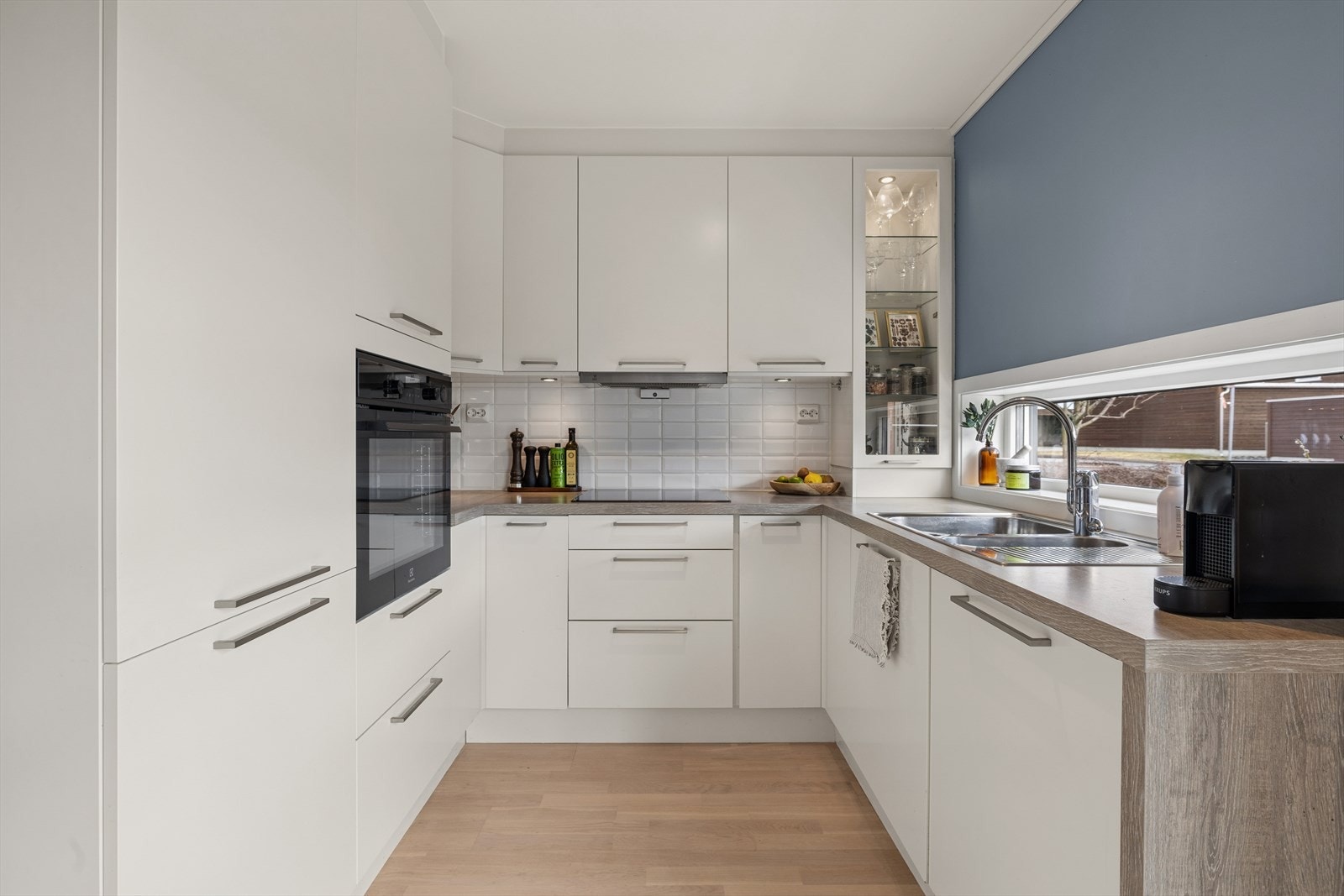 Lyst og stilrent kjøkken med integrert komfyr, platetopp, oppvaskmaskin og kjøl-/fryseskap. Galleribilde