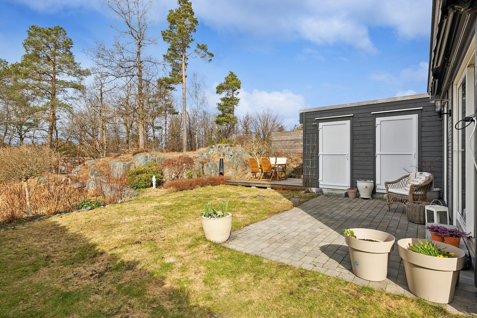 Lun og usjenert bakhage med sen kveldssol. Bod for lagring og adkomst til garasje. Elektrisk markise over uteplass Galleribilde