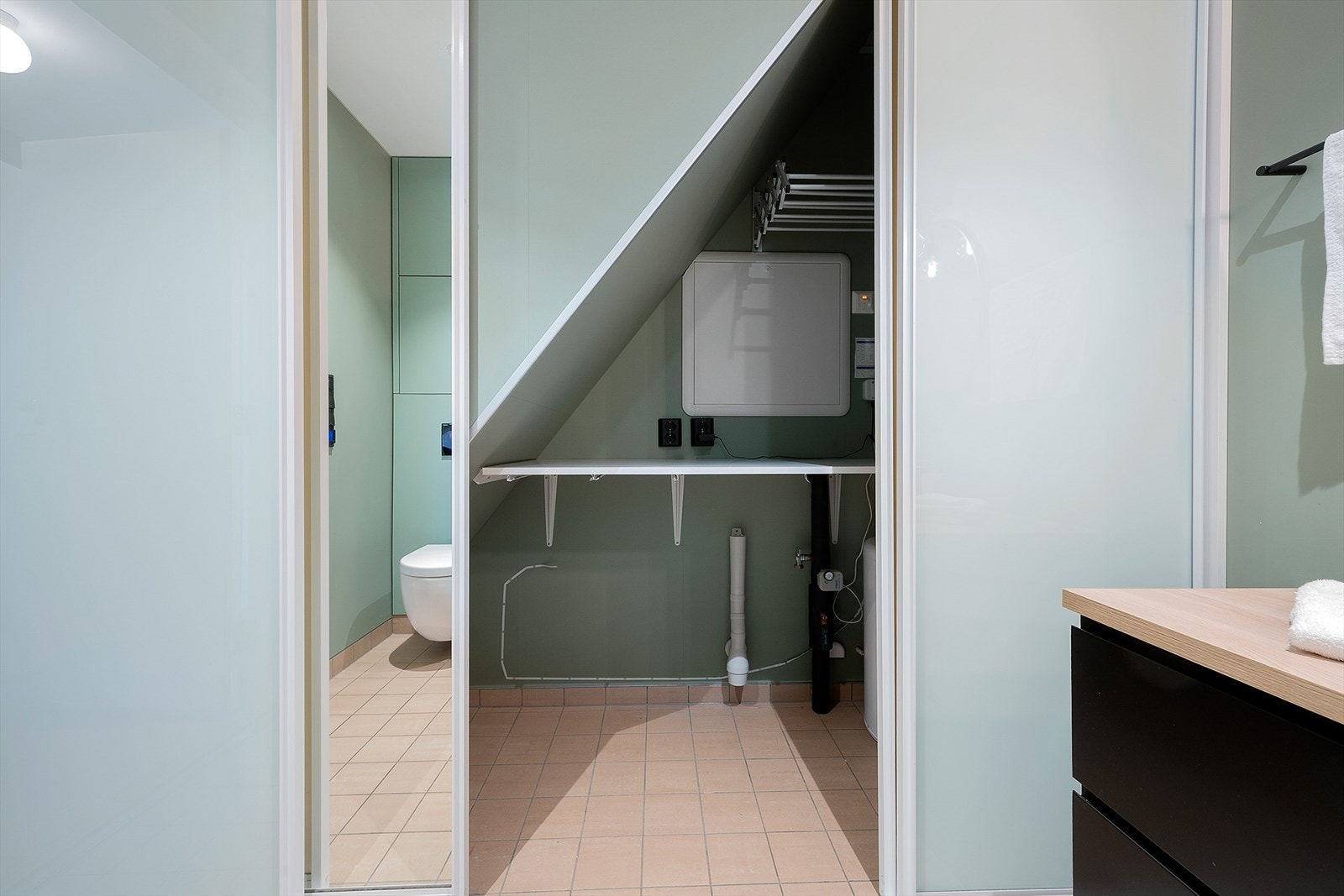 Badet har vaskeromsnisje avskjermet med gulv-til-tak skyvedører i glass og speil. Galleribilde