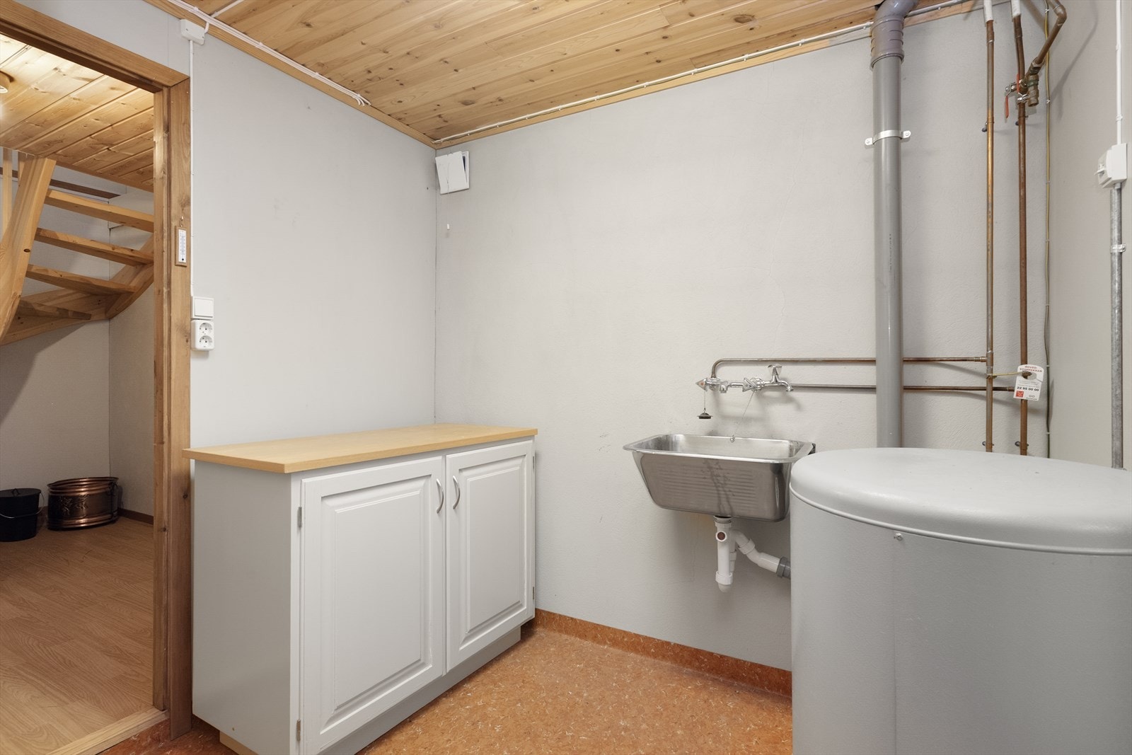 I tilbygget del er det bla. et vaskerom fra 1983 med belegg på gulv og malt puss/ plater på vegger. Rommet har innredning med benkeplate og underskap, samt utslagsvask og opplegg for vaskemaskin. Ventilasjon via ventil i vegg. 120l vvt fra 1986. Galleribilde