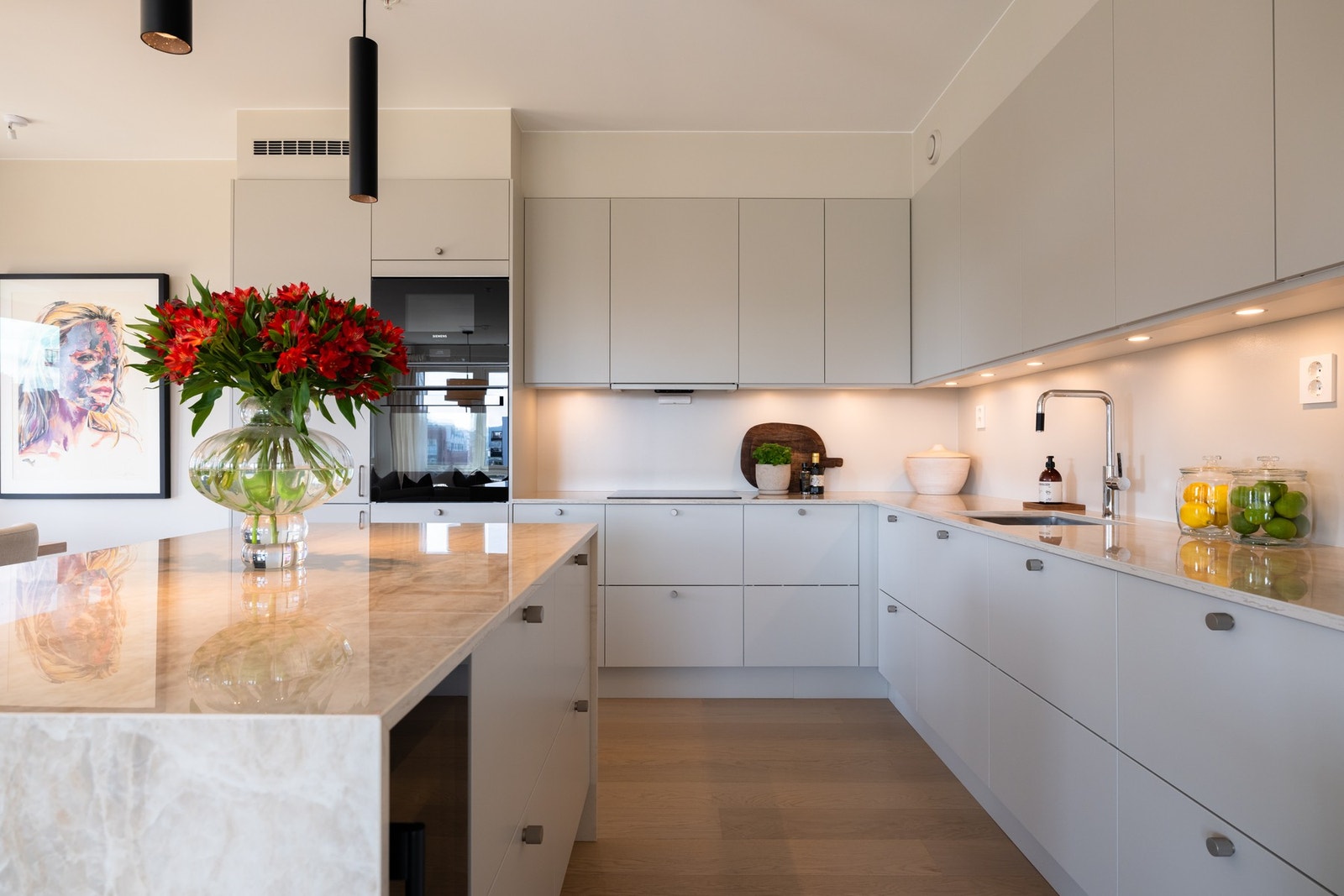 Påkostet med eksklusiv Dekton keramisk benkeplate. Kjøkkenøyen er strukket med benkeplater langs tre sider Galleribilde