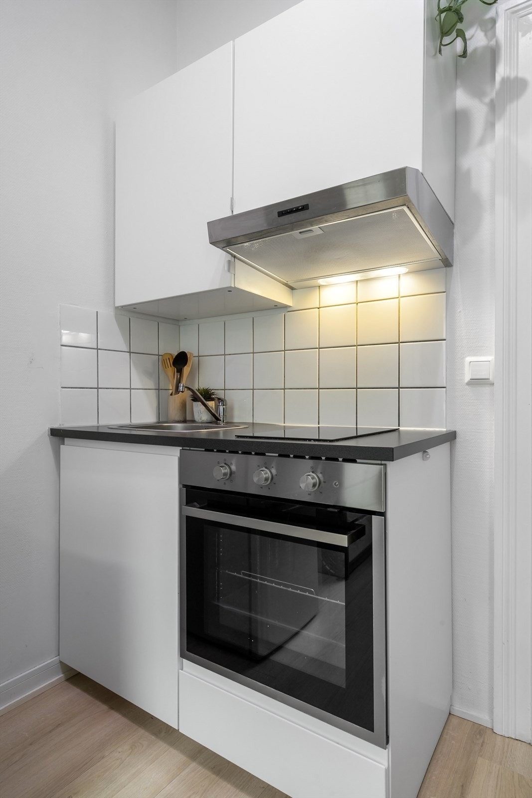 Kjøkken har slette fronter, fliser på vegg, laminat benkeplate og kullfilterventilator. Stekeovn og platetopp er integrert i innredningen. Galleribilde