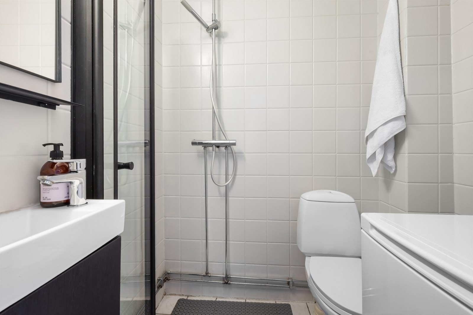 Bad med servantinnredning, toalett, dusj med innfellbar dør i herdet glass og opplegg for vaskemaskin. Galleribilde