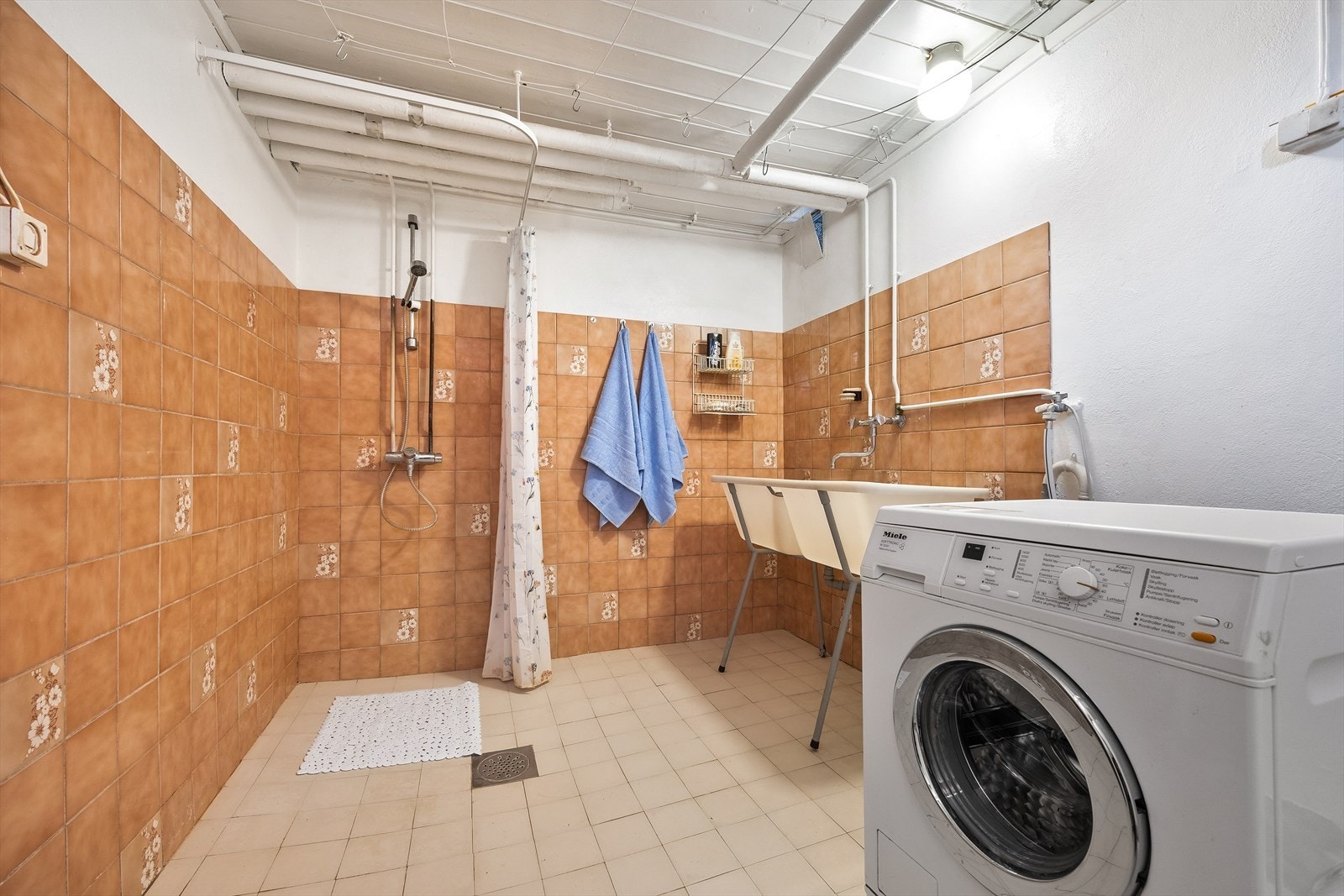Separat vaskerom i kjelleren med opplegg for vaskemaskin, utslagsvask og et dusjhjørne. Galleribilde
