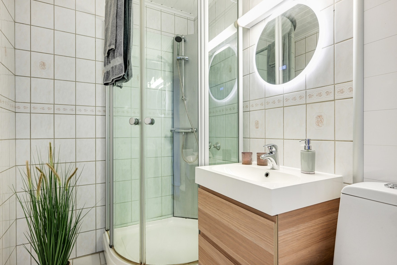Badet fremstår som praktisk med vegghengt speil med ringbelysning og antidugg. Veggene utenfor dusjsonen er nylig skiftet ut til moderne våtromsplater Galleribilde