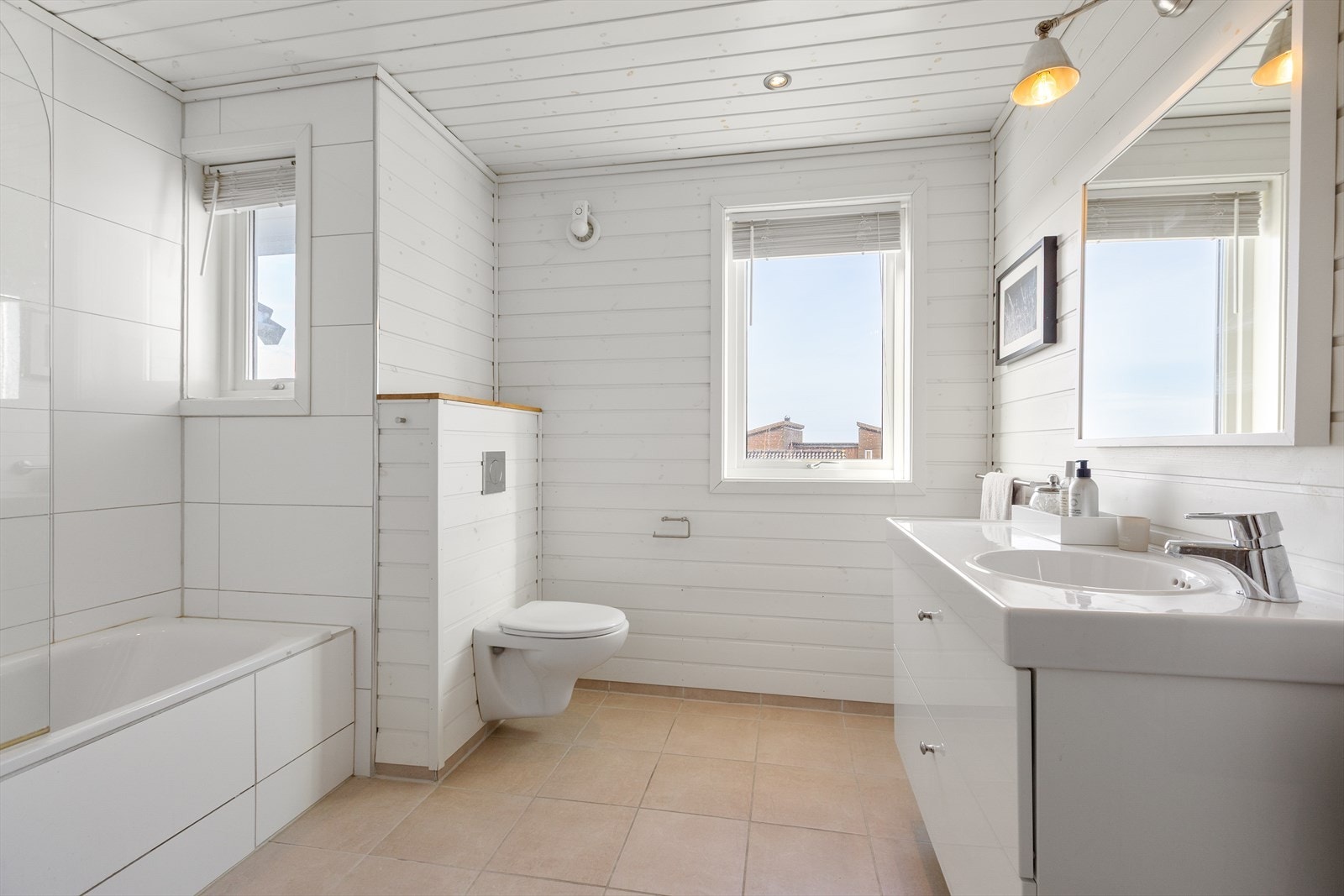 Baderommet er innredet med vegghengt toalett, badekar og baderomsservant. Galleribilde