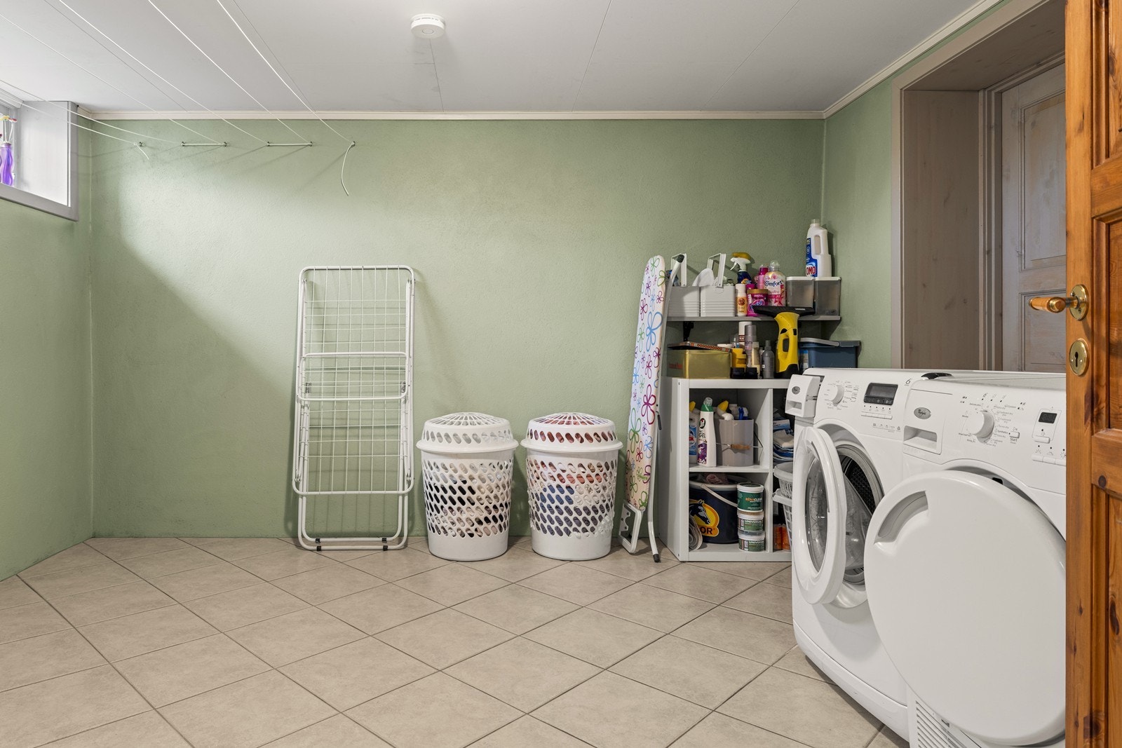 Separat rom innredet som vaskerom i kjelleren med flislagt gulv med gulvvarme og opplegg for vaskemaskin. Galleribilde