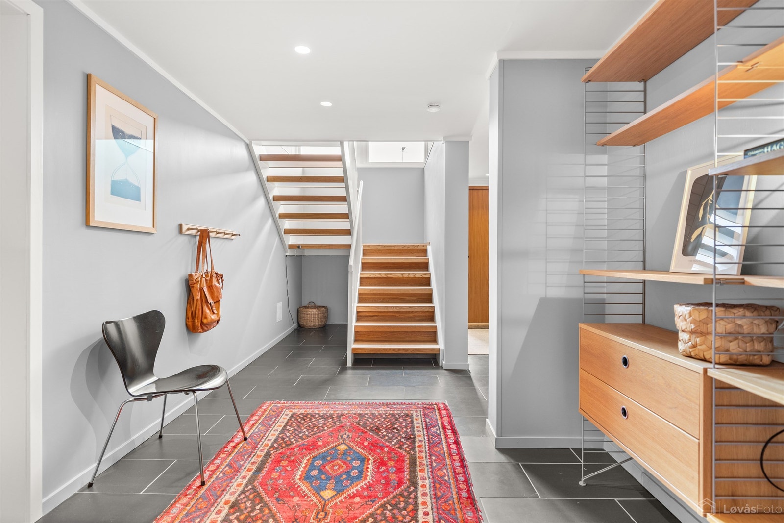 Romslig hall med gulvfliser med varmekabler, downlights i himling og plass til møblering. Entréen har ny påkostet ytterdør fra Bovalls i 2024 med elektronisk kodelås Galleribilde