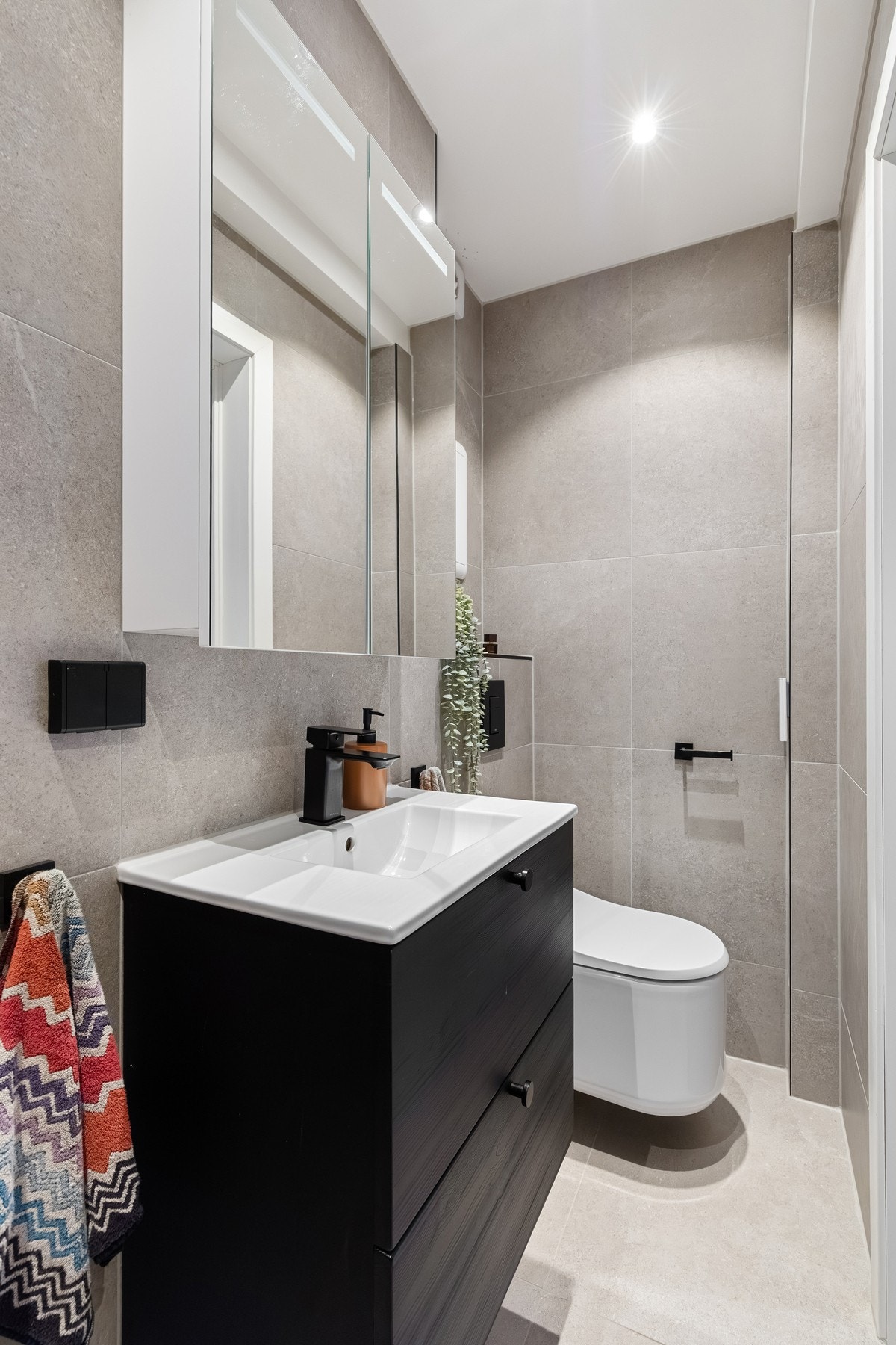 Badet er innredet med vegghengt toalett, dusjnisje, servantskap med nedfelt servant og veggskap. Galleribilde