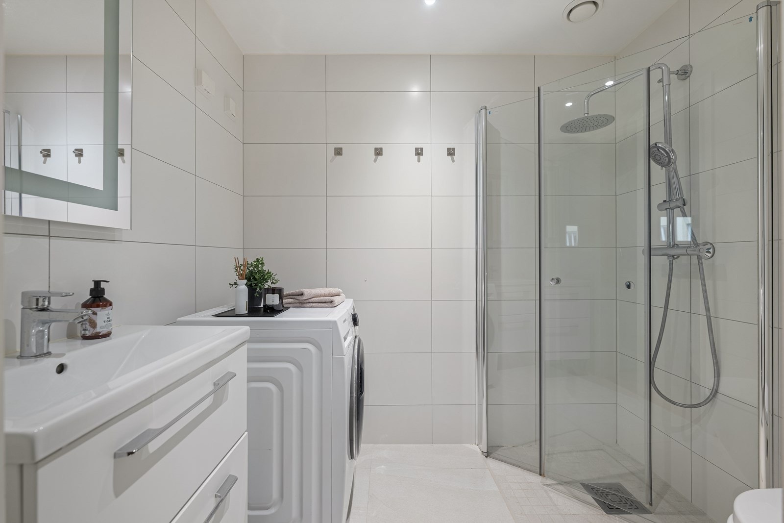 Badet har flislagte vegger og gulv i lyse farger, og det er varmekabler i gulvet for ekstra komfort. Gulvflisene ble lagt nye i 2023. Galleribilde