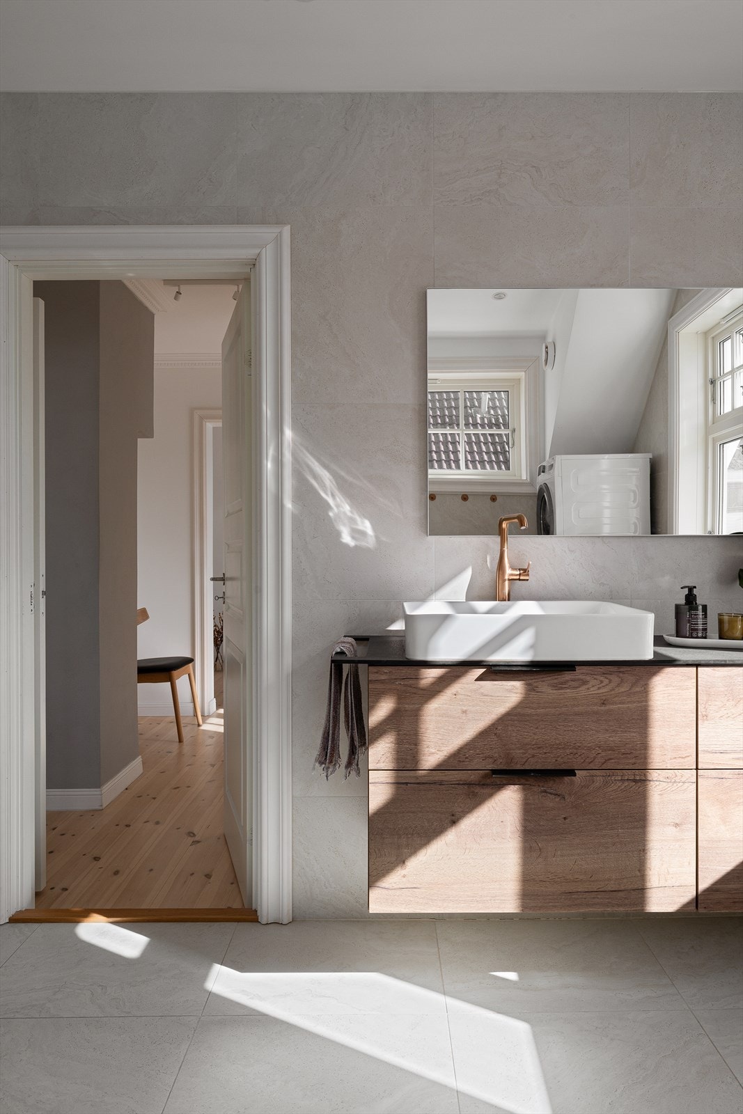 Badet har moderne innredning og er lekkert helfliset. Det er utstyrt med vegghengt toalett, dusjhjørne med dusjvegger, servant og opplegg for vaskemaskin. Galleribilde