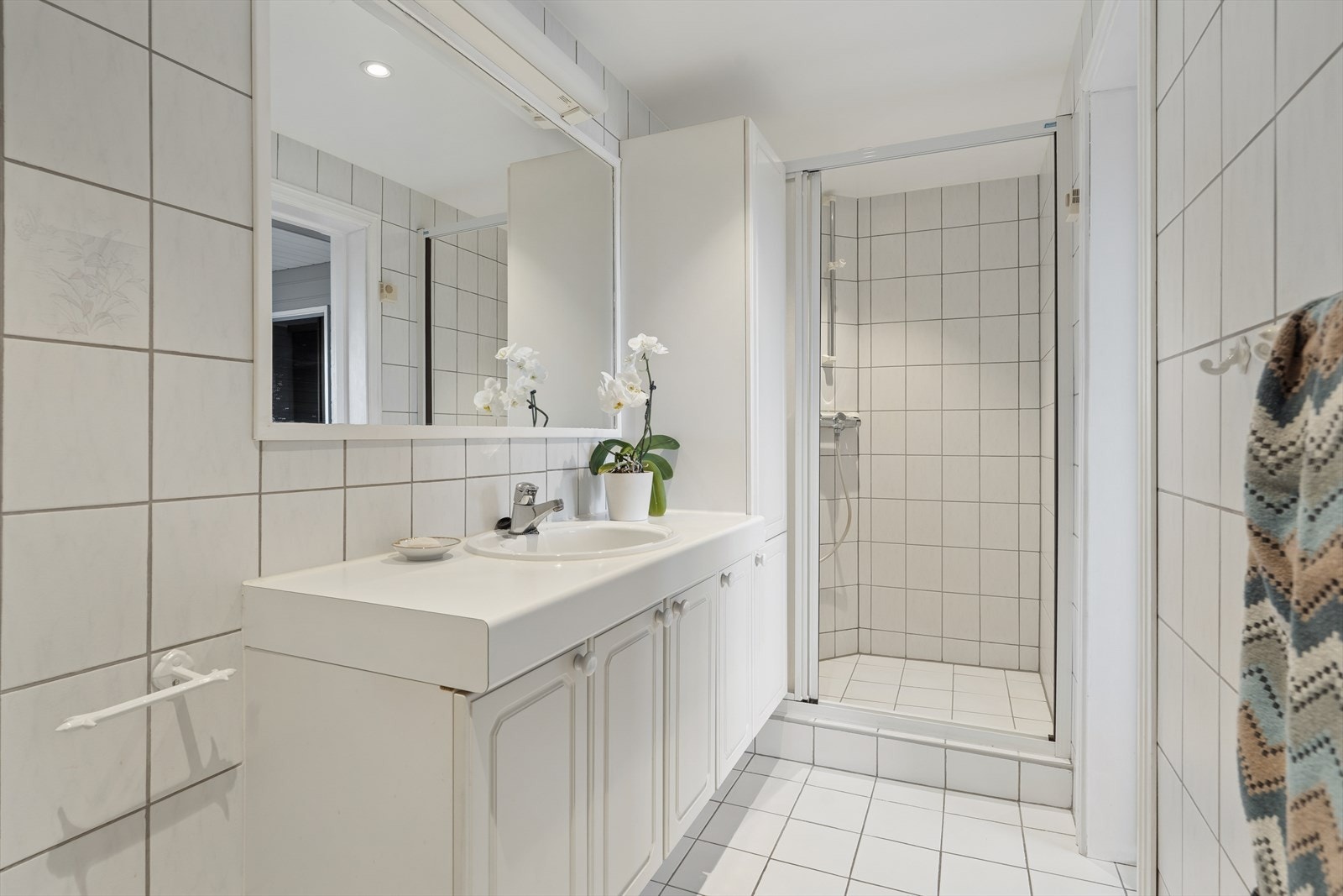 Badet i underetasjen er fra 1995 og har fliser på gulv med gulvvarme - Innredning med servant, speil og en egen dusjnisje med skyvedør. Galleribilde