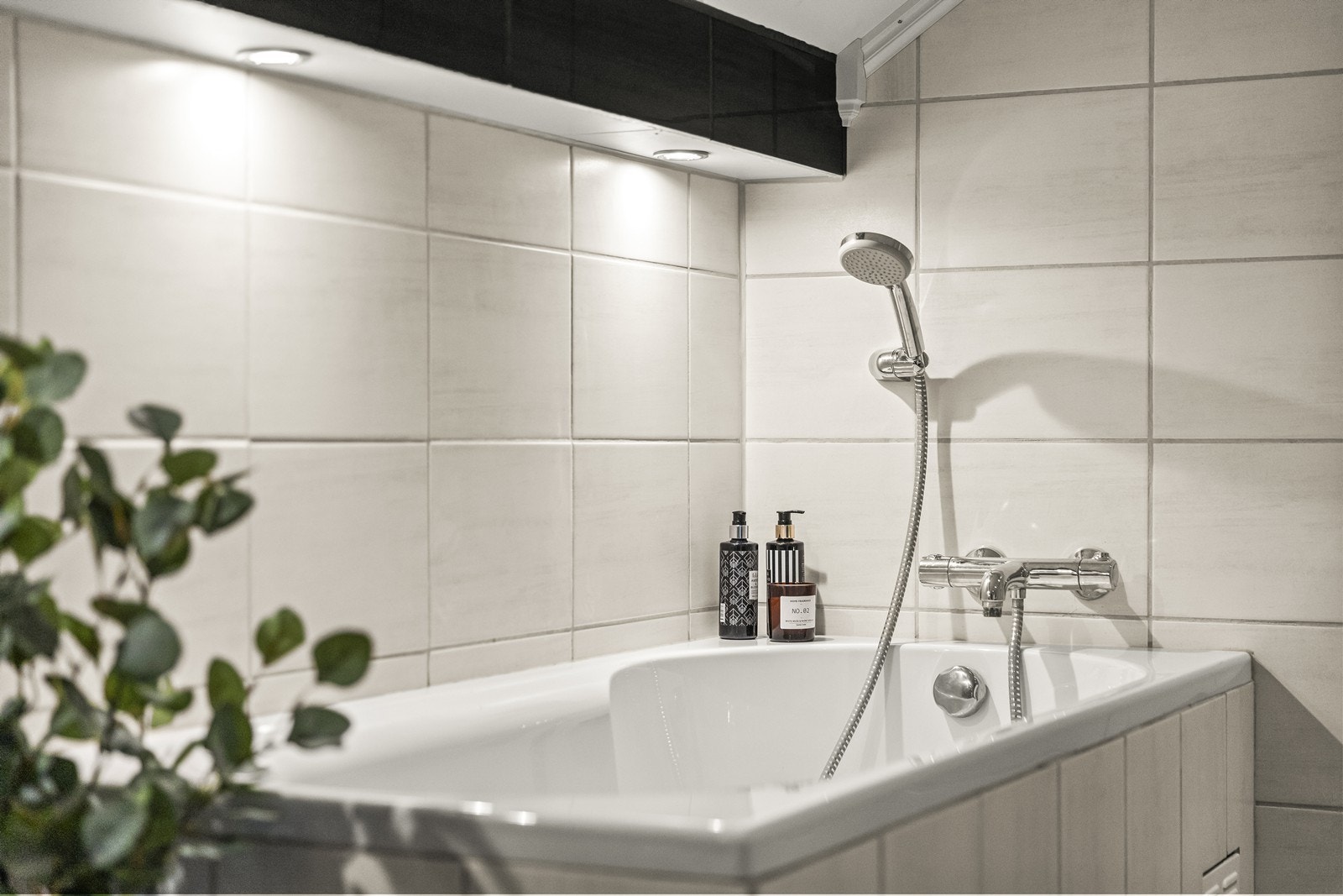 Badet i 2. etasje har fliser på vegger og gulv, med elektriske varmekabler og et badekar med hånddusj. Galleribilde