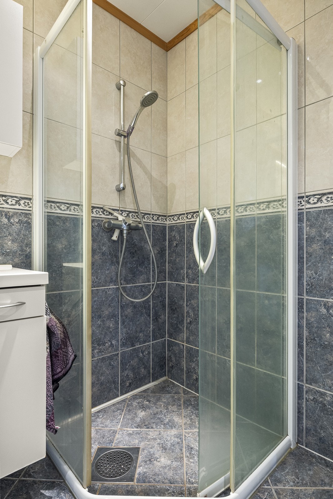 Dusjen er plassert i hjørnet av badet og har dører av glass. Galleribilde