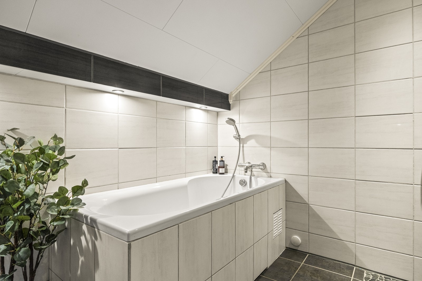 Badet er utstyrt med downlights i taket og har et badekar med hånddusj. Galleribilde