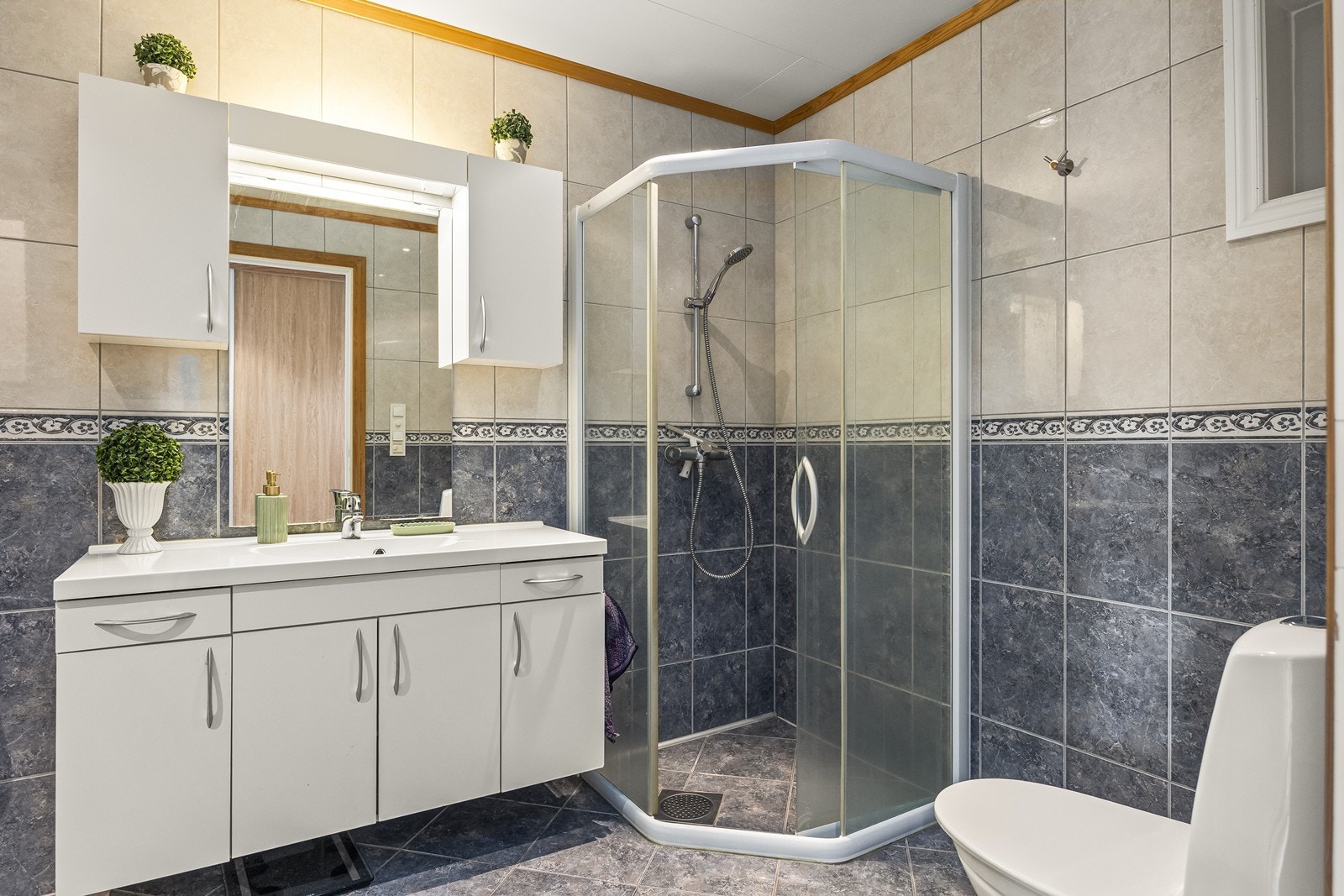 Badet i 1. etasje har flislagte overflater med integrert baderomsinnredning. Galleribilde