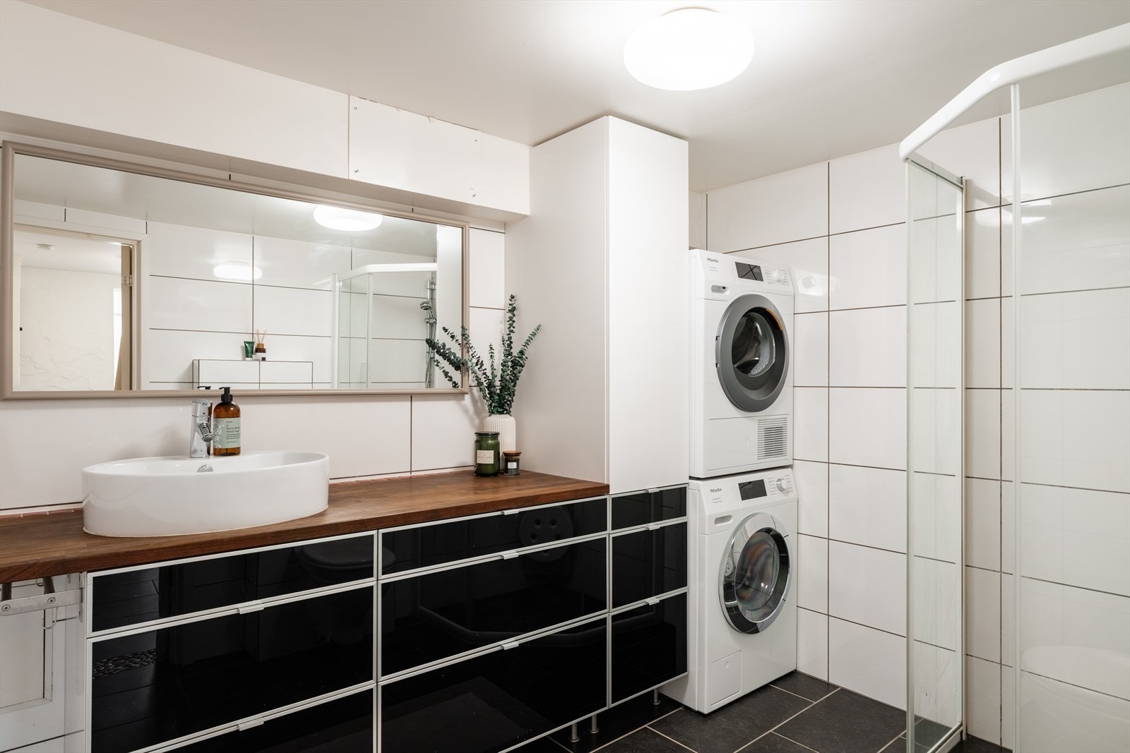 Bad/vaskerom i underetasjen er innredet med tilsvarende løsning med benkeplate og servant, vegghengt toalett og dusjsone, samt opplegg for vaskemaskin. Badet i underetasjen er byggemeldt som bod og ikke bruksendret. Se pkt. om ferdigattest. Galleribilde