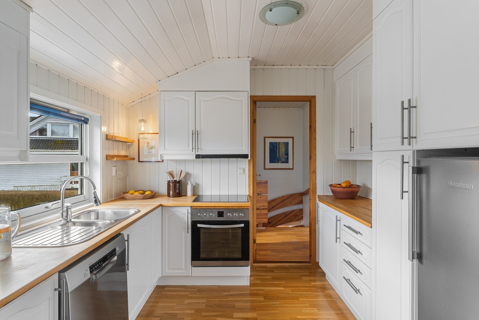 Kjøkkenet har en praktisk L-form med profilerte fronter og benkeplate i tre. Kjøkkenventilator har avtrekk ut. Galleribilde