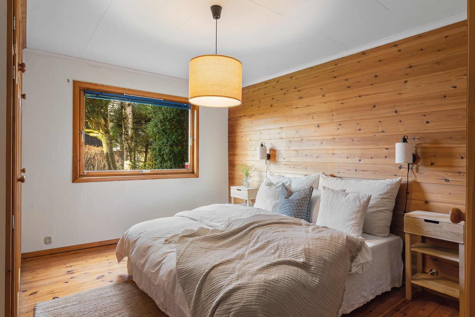 Hovedsoverommet har en lun atmosfære med furugulv og en fondvegg med trepanel. Galleribilde