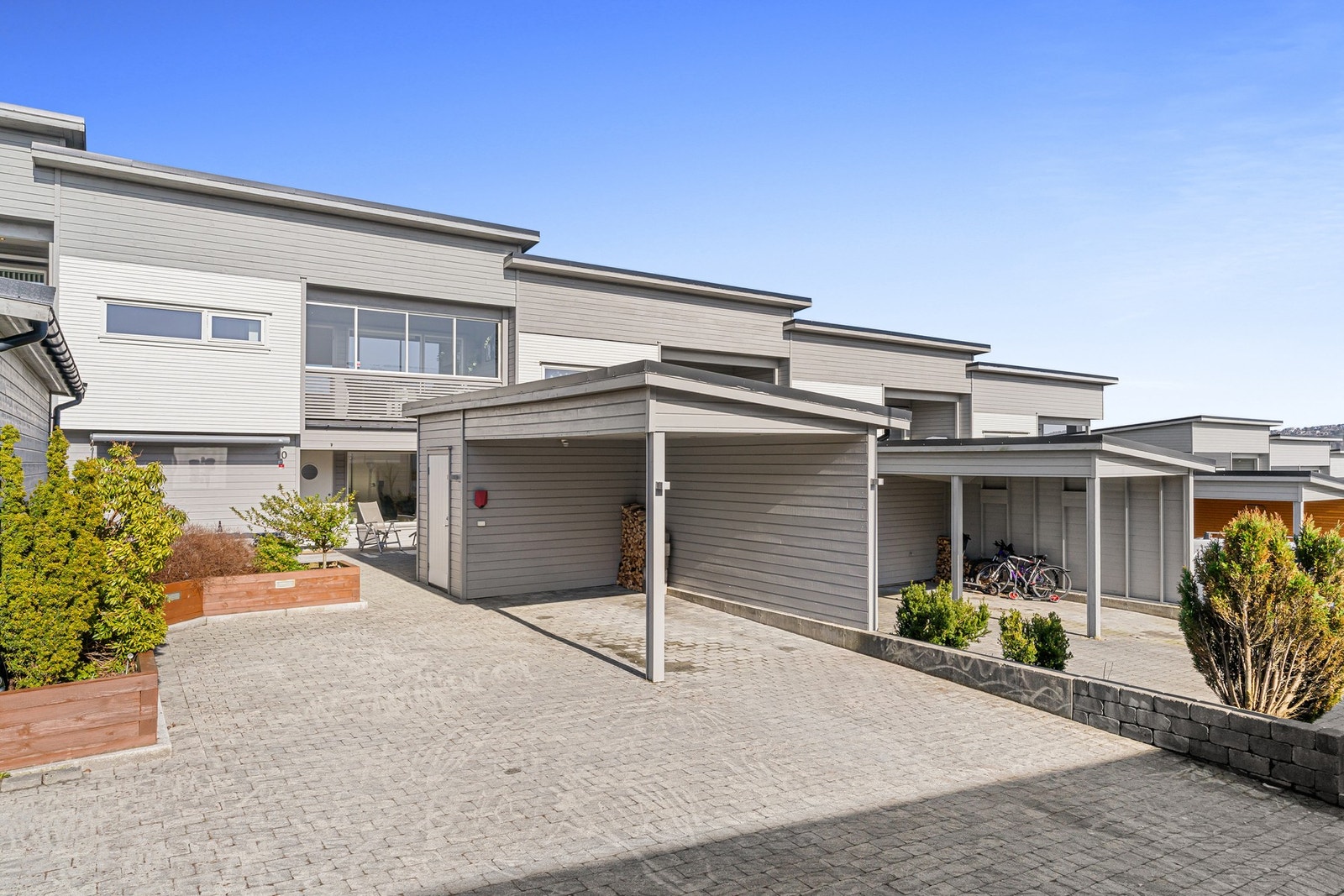 Boligen har et pent opparbeidet uteområde med steinbelagt gårdsrom, carport og en lun sittegruppe Galleribilde