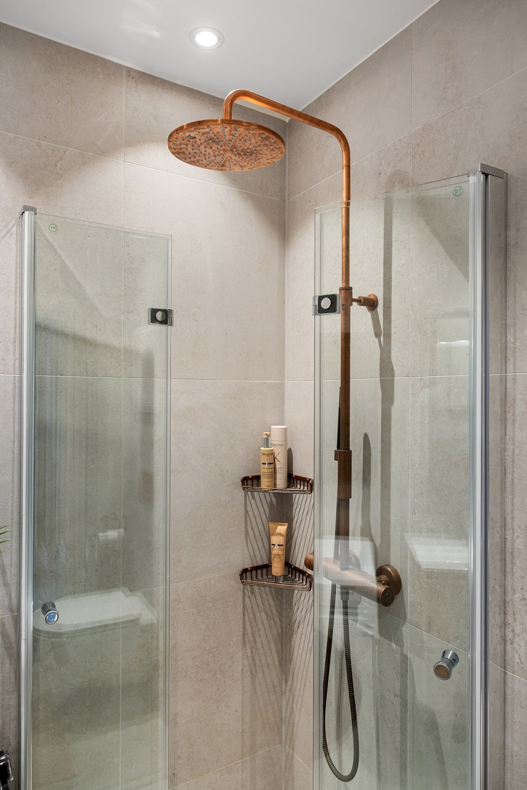 Praktiske løsninger inkluderer et dusjhjørne med innfellbare dusjdører og blandebatteri med to dusjhoder Galleribilde