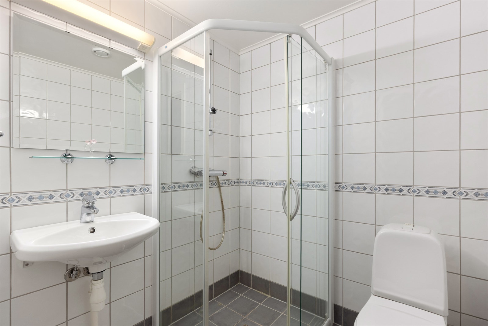 Bad 2 er flislagt med dusj, enkel servant og gulvstående WC Galleribilde