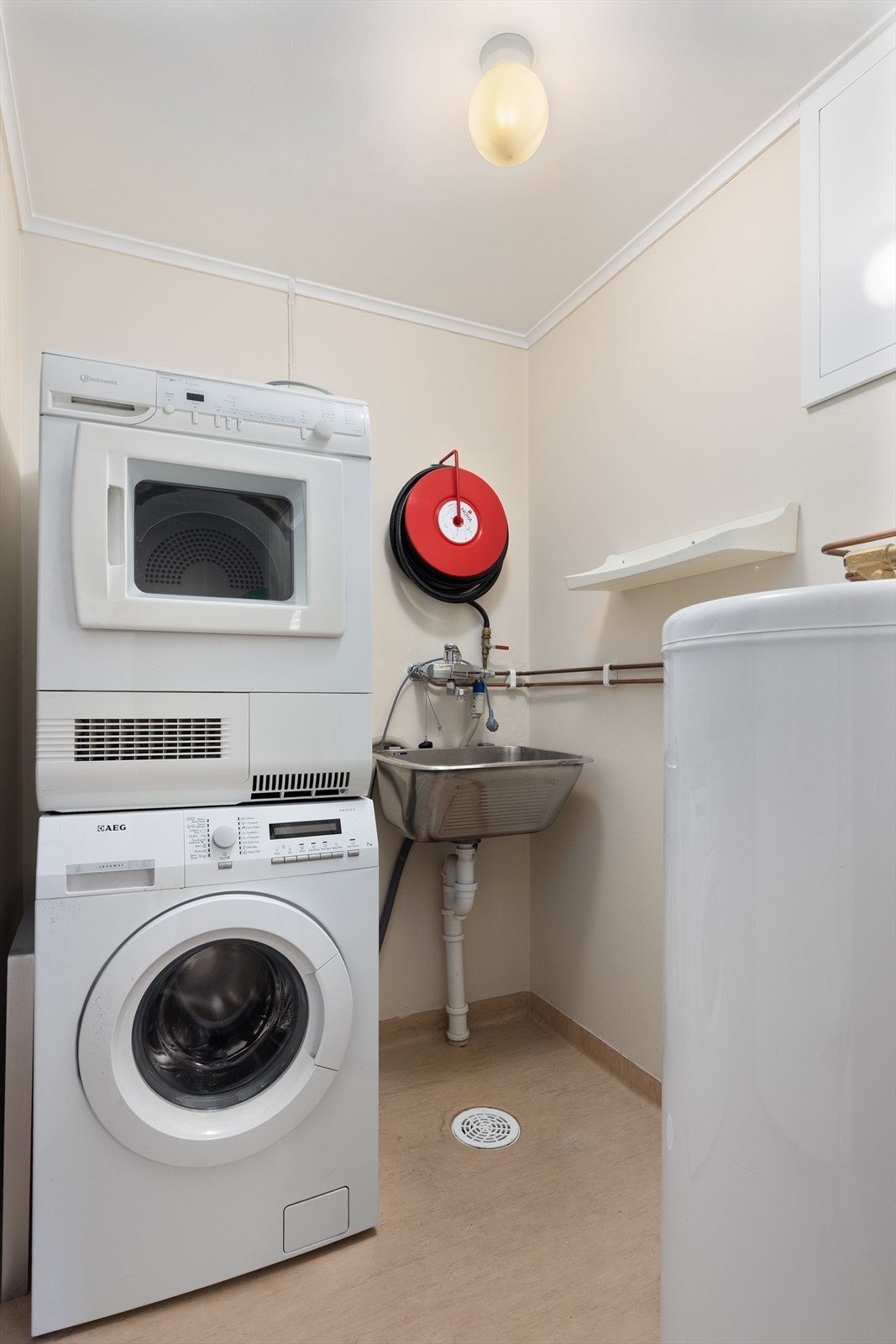 Praktisk vaskerom med opplegg for vaskesøyle. Her er også varmtvannsbereder og enhet for sentralstøvsuger plassert Galleribilde