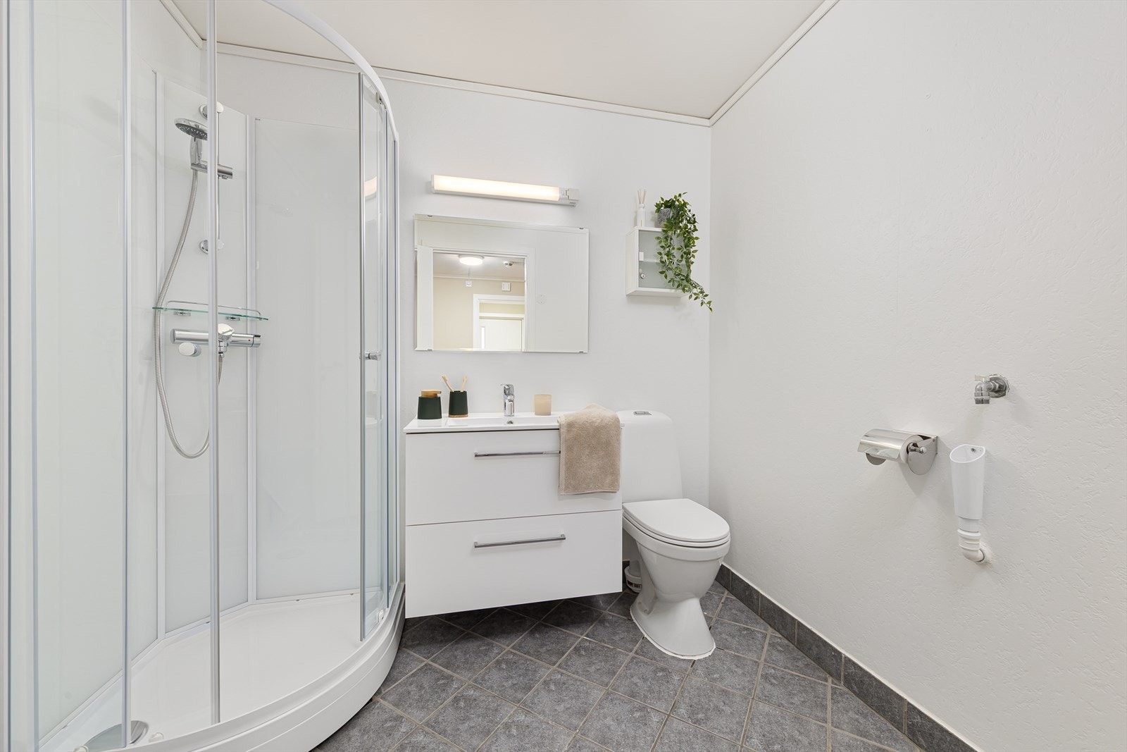 Lyst og pent bad med flislagt gulv og varmekabler. Badet ble i 2026 utstyrt med nytt dusjkabinett, toalett og en moderne baderomsinnredning. Opplegg for vaskemaskin. Galleribilde