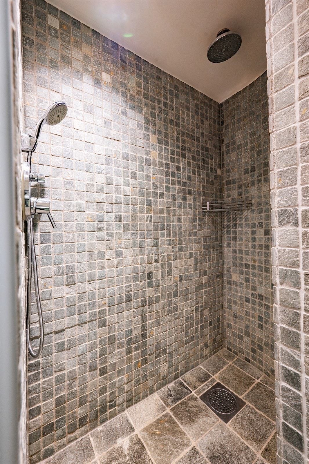 Badet består av vegghengt toalett, dusj direkte på gulv og servantskap med glatte fronter. Galleribilde