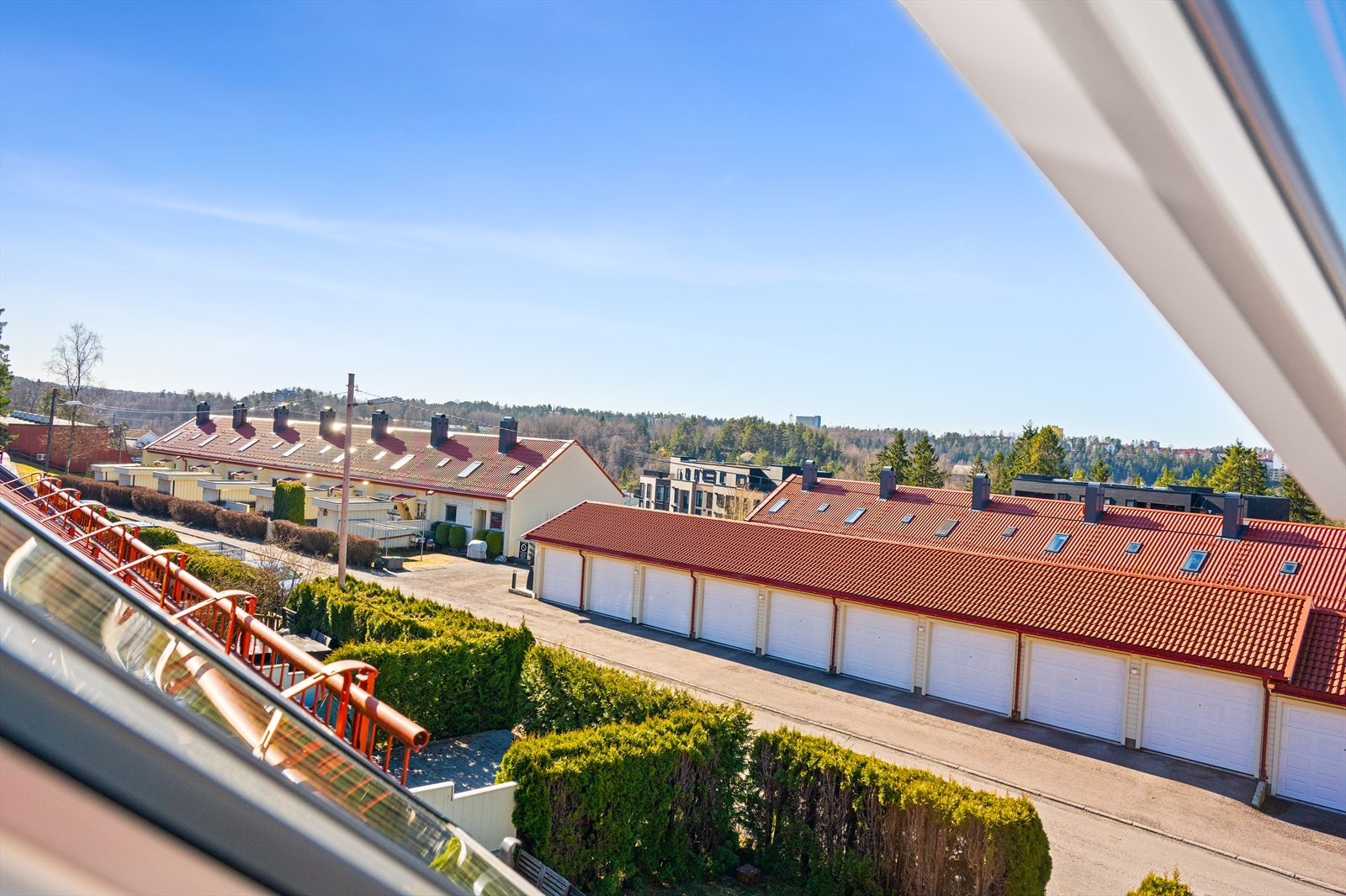 Et oversiktsbilde tatt fra takvinduene gir god utsikt over nabolaget, med rekkehusbebyggelsen og tilhørende garasjer. Galleribilde