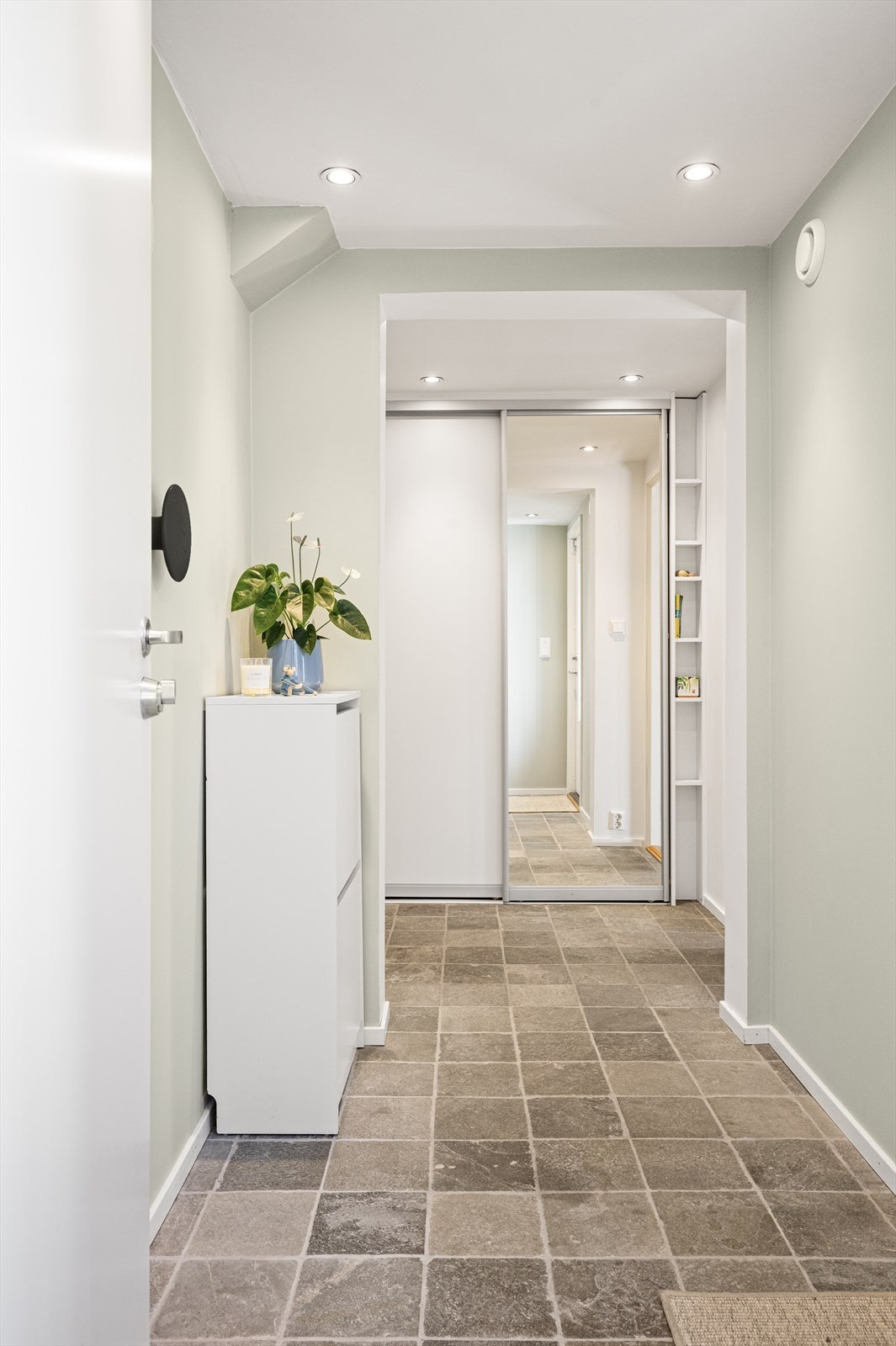 Deretter går vi via entreen og inn til gangen. Her blir vi møtt av fliser på gulvet og innfelt belysning som sammen skaper et ryddig og stilrent uttrykk - og gir et svært godt førsteinntrykk allerede idet man kommer inn i boligen. Galleribilde