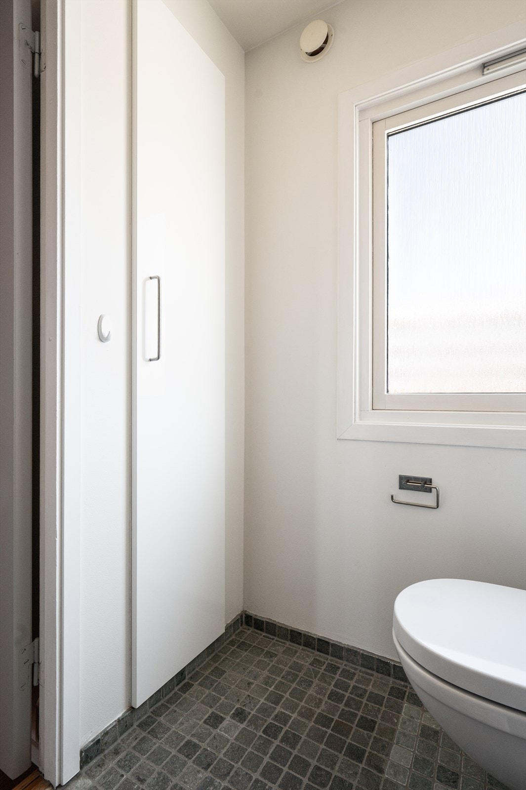 Badet har et vegghengt toalett og et praktisk skap. Galleribilde