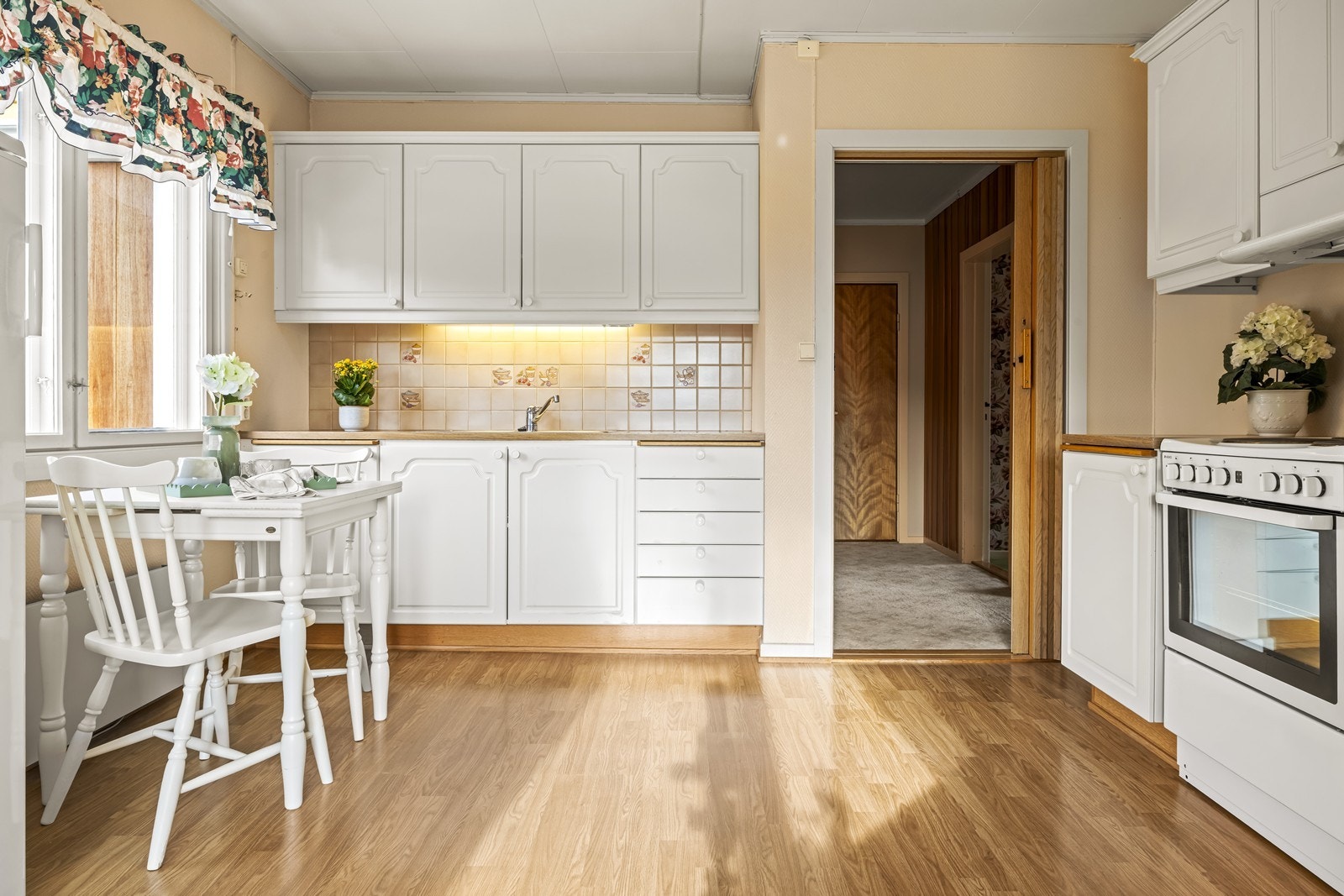 Gulvet på kjøkkenet er belagt med laminat, og det er fliser på veggen over benken. Galleribilde