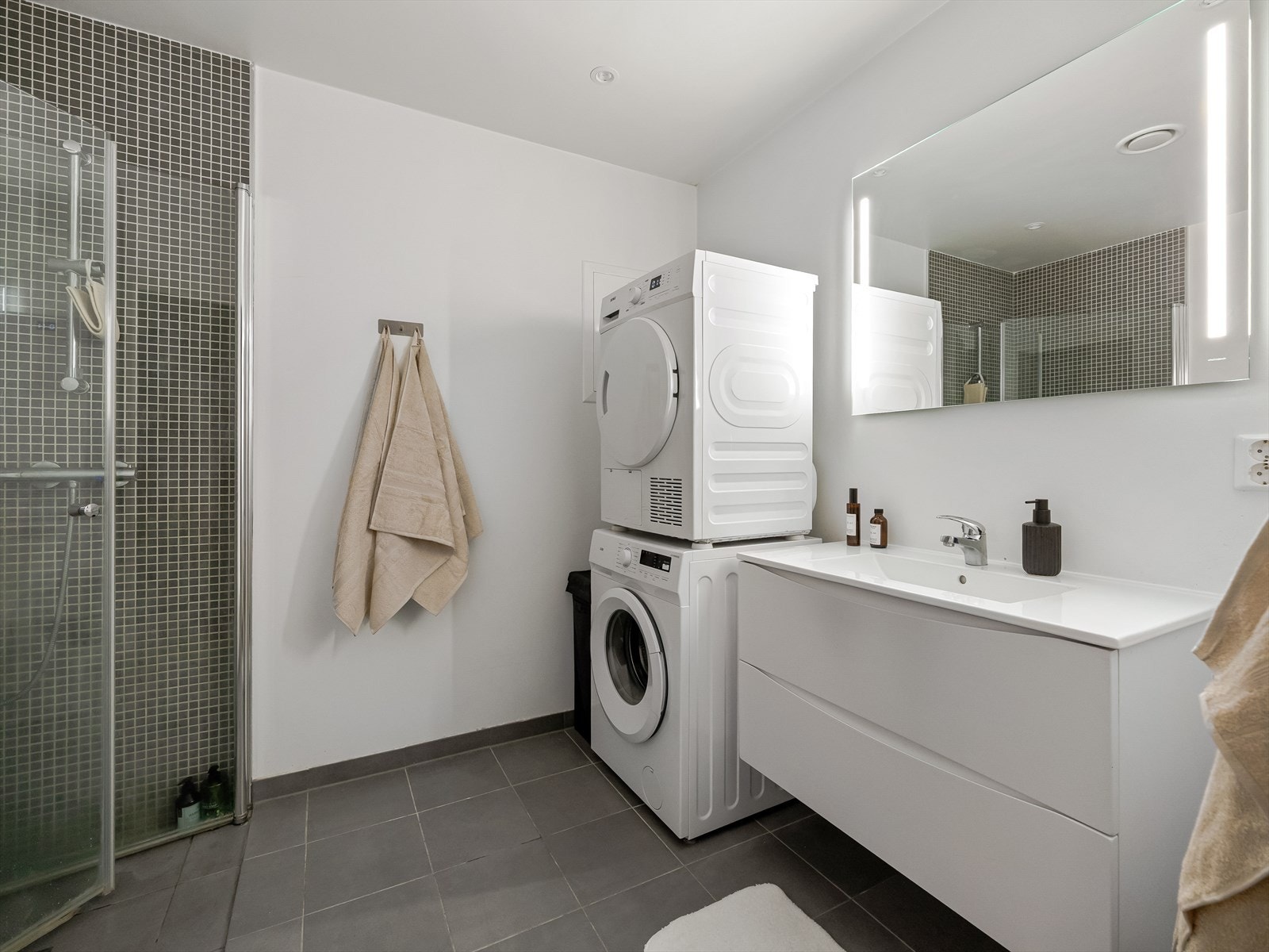 Ellers består badet av servantinnredning med oppbevaring i underkant, speil med integrerte lys, vegghengt toalett, dusjnisje og opplegg til både vaskemaskin og tørketrommel. Galleribilde